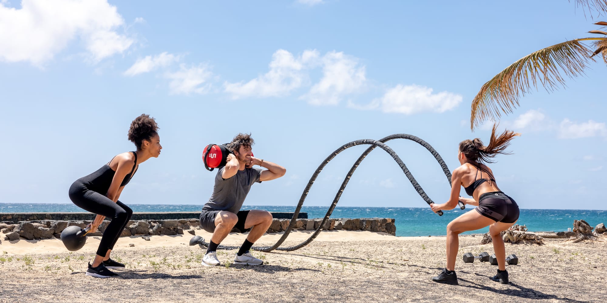 a group of people playing with a rope on a beach