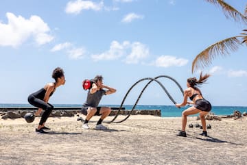 a group of people playing with a rope on a beach