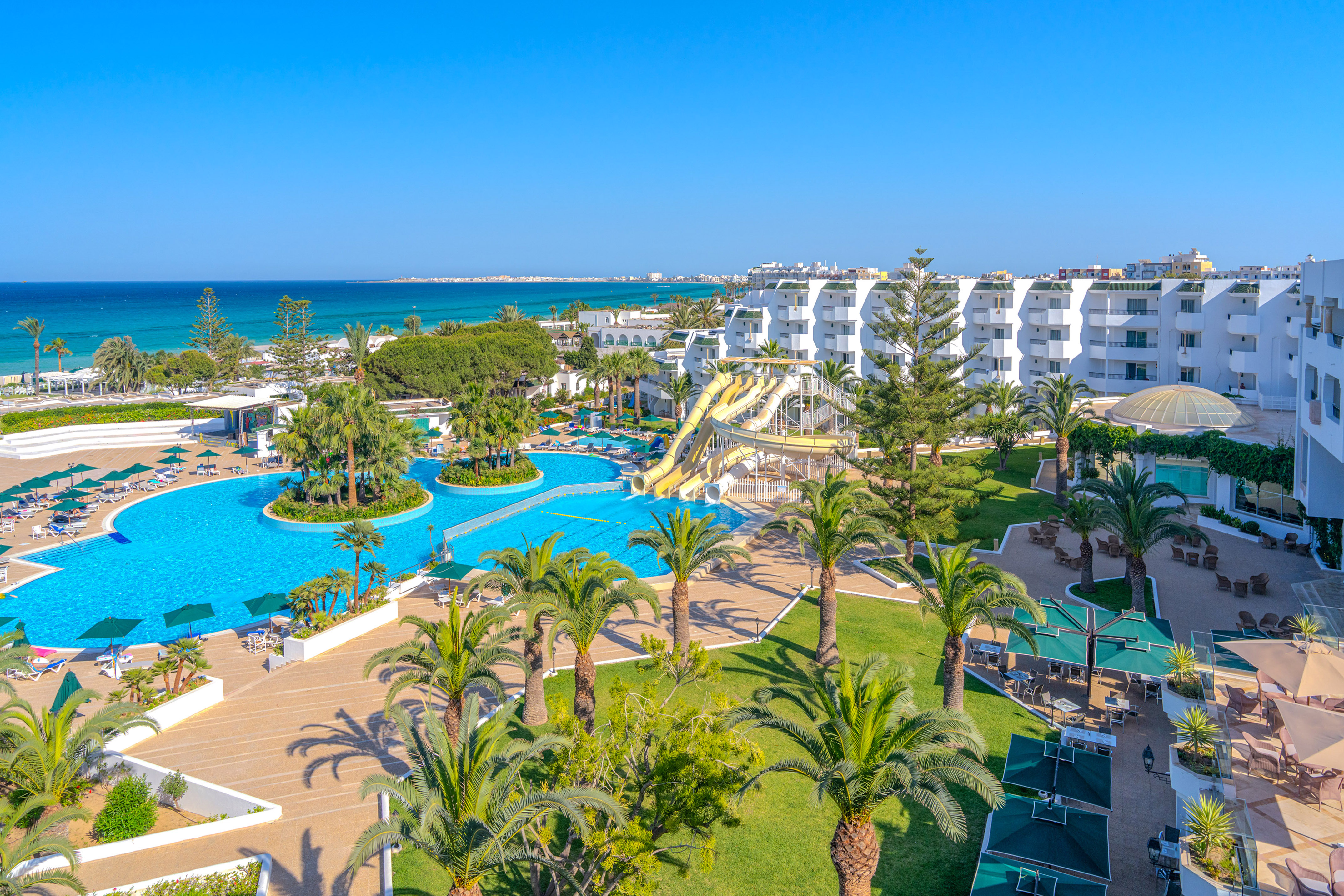Tropical beachfront resort with pools, waterslides, palm trees, and ocean view.