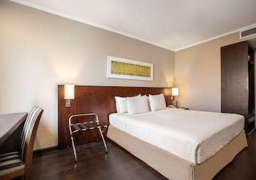 a bed with white sheets and a wood headboard in a room