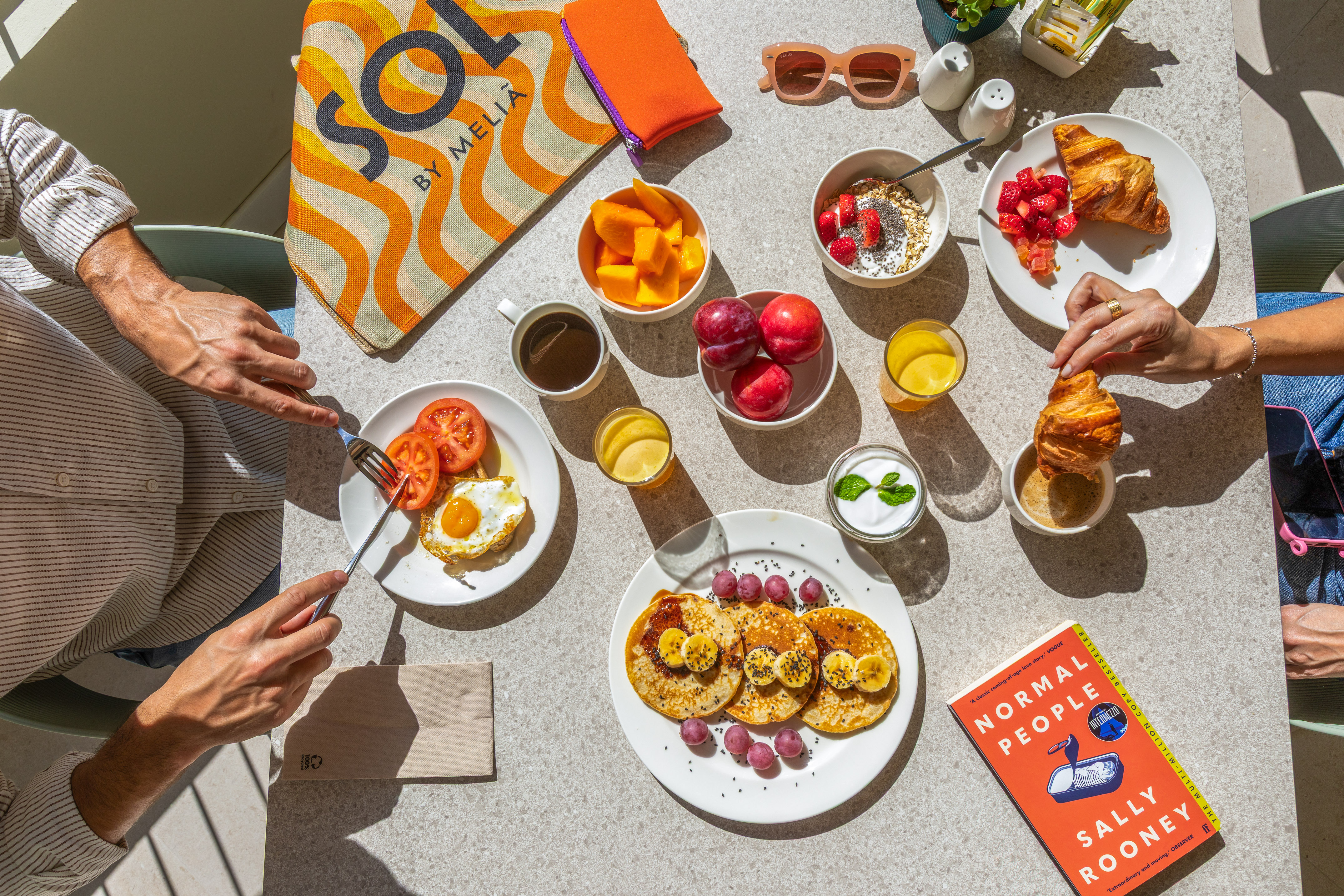 Sunny breakfast spread with pancakes, eggs, fruit, and coffee at a Meliã hotel.