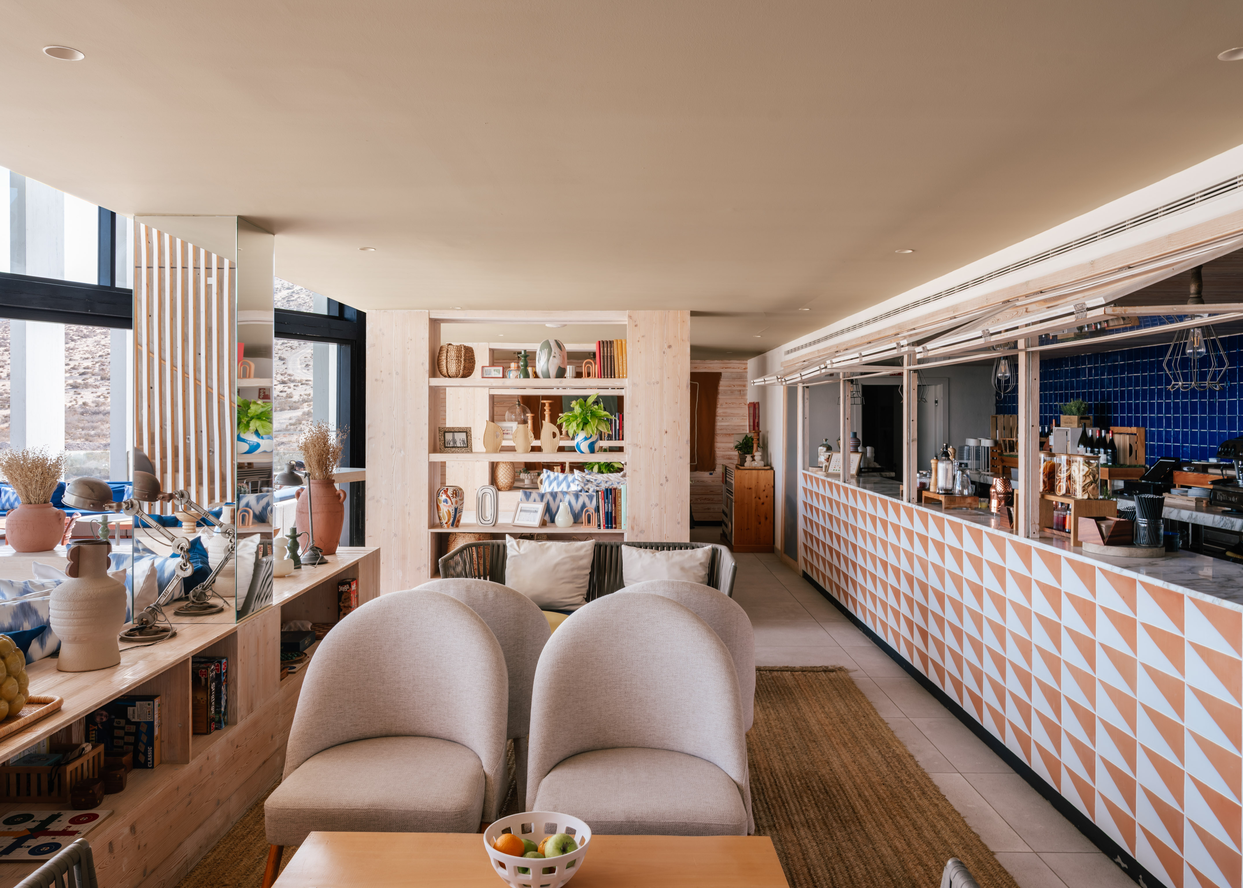 Modern hotel lounge and bar with light wood shelves and geometric counter.