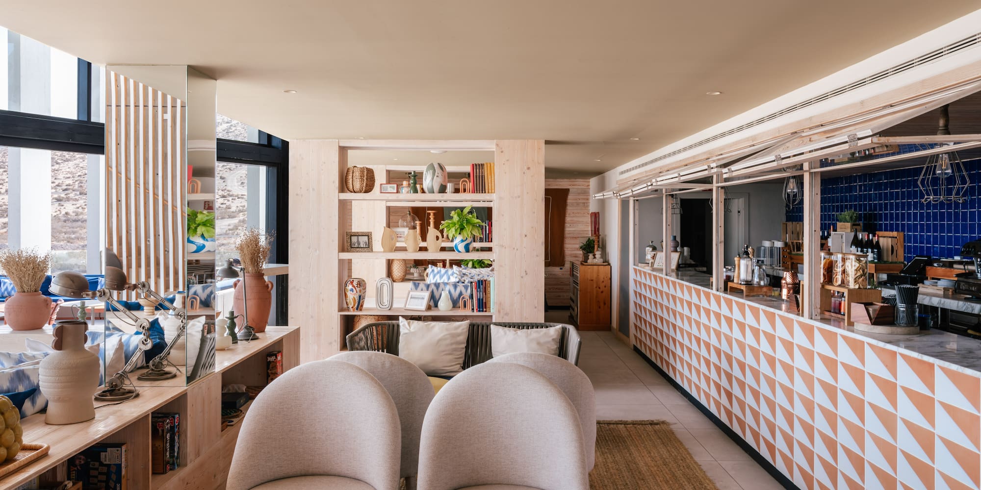 Modern hotel lounge and bar with light wood shelves and geometric counter.