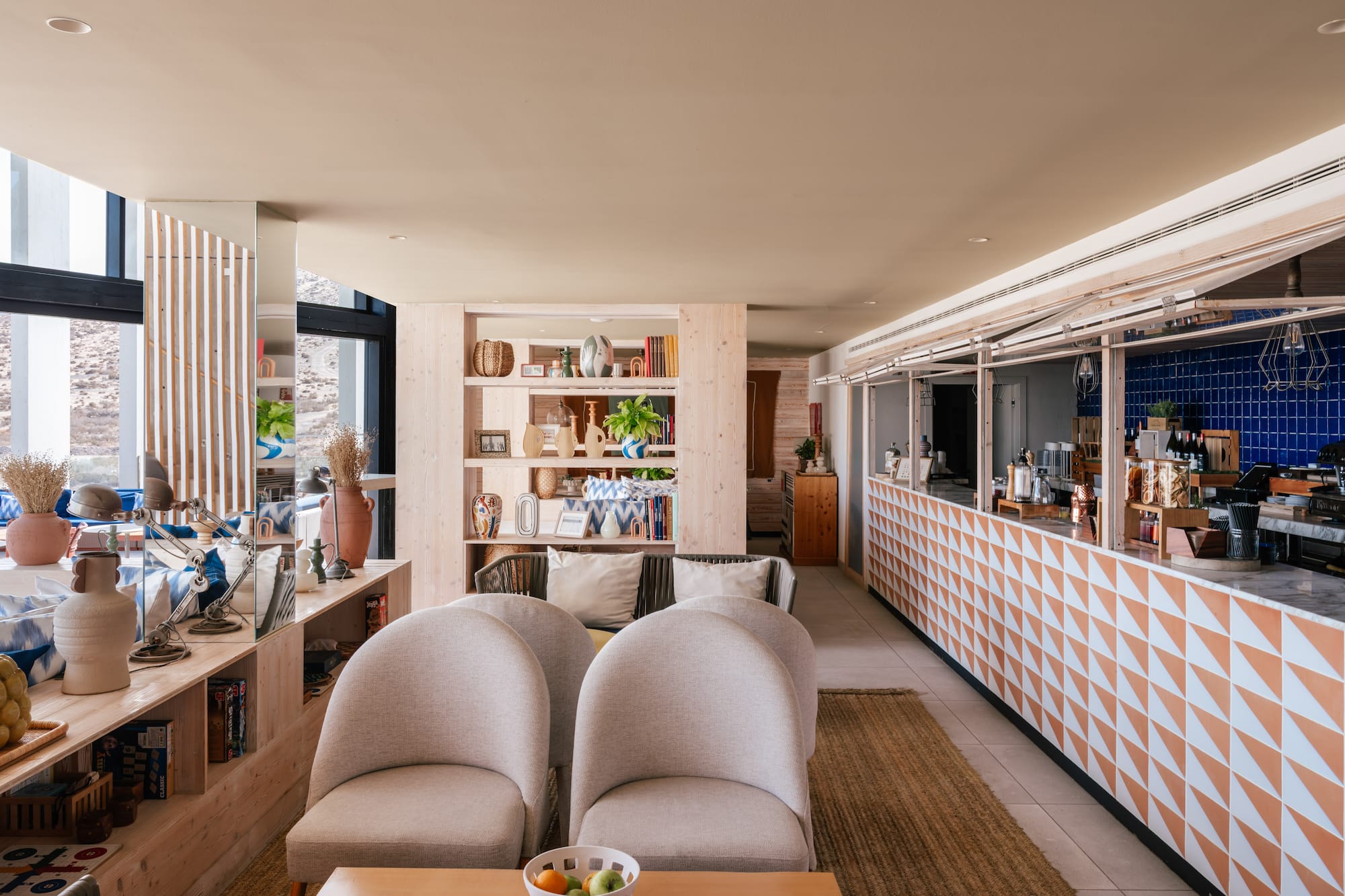 Modern hotel lounge and bar with light wood shelves and geometric counter.