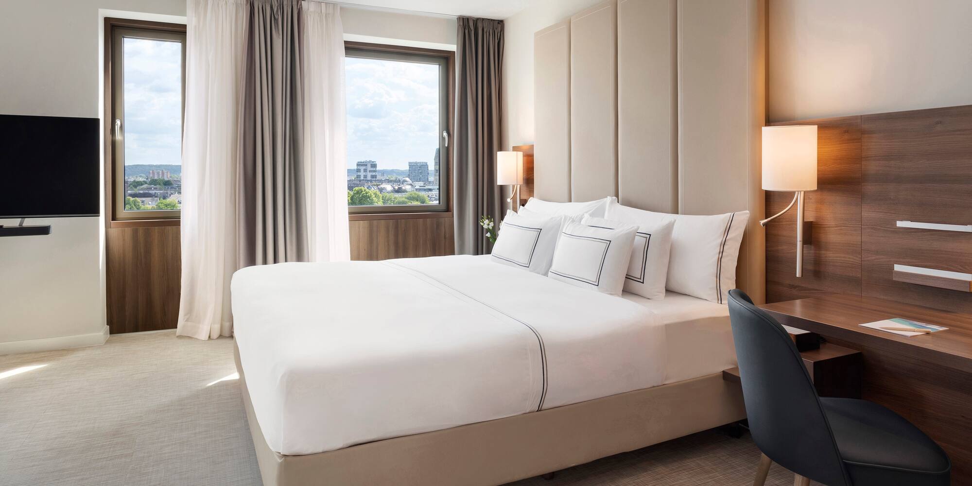 a bed with a chair and a desk in a hotel room