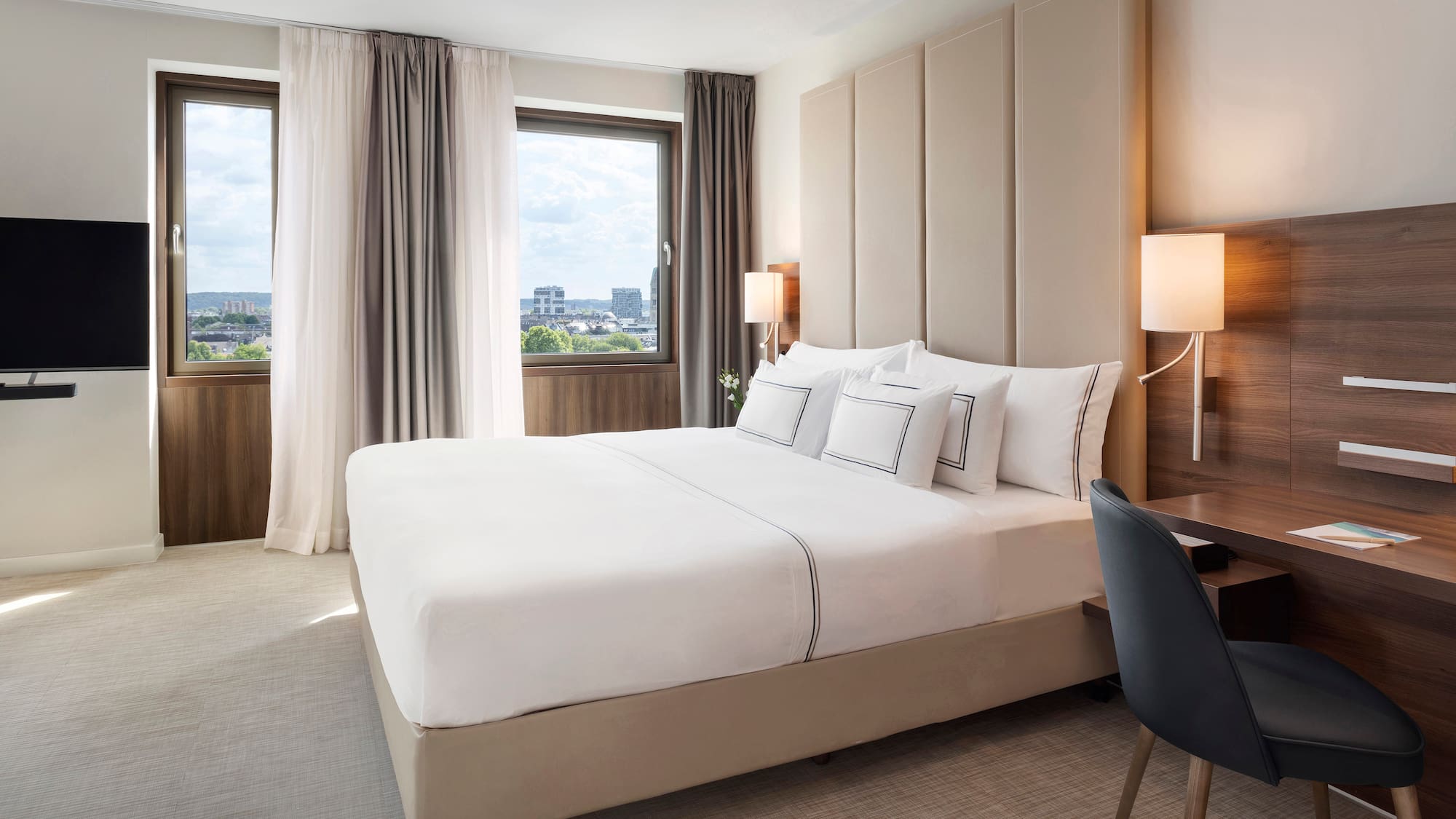 a bed with a chair and a desk in a hotel room
