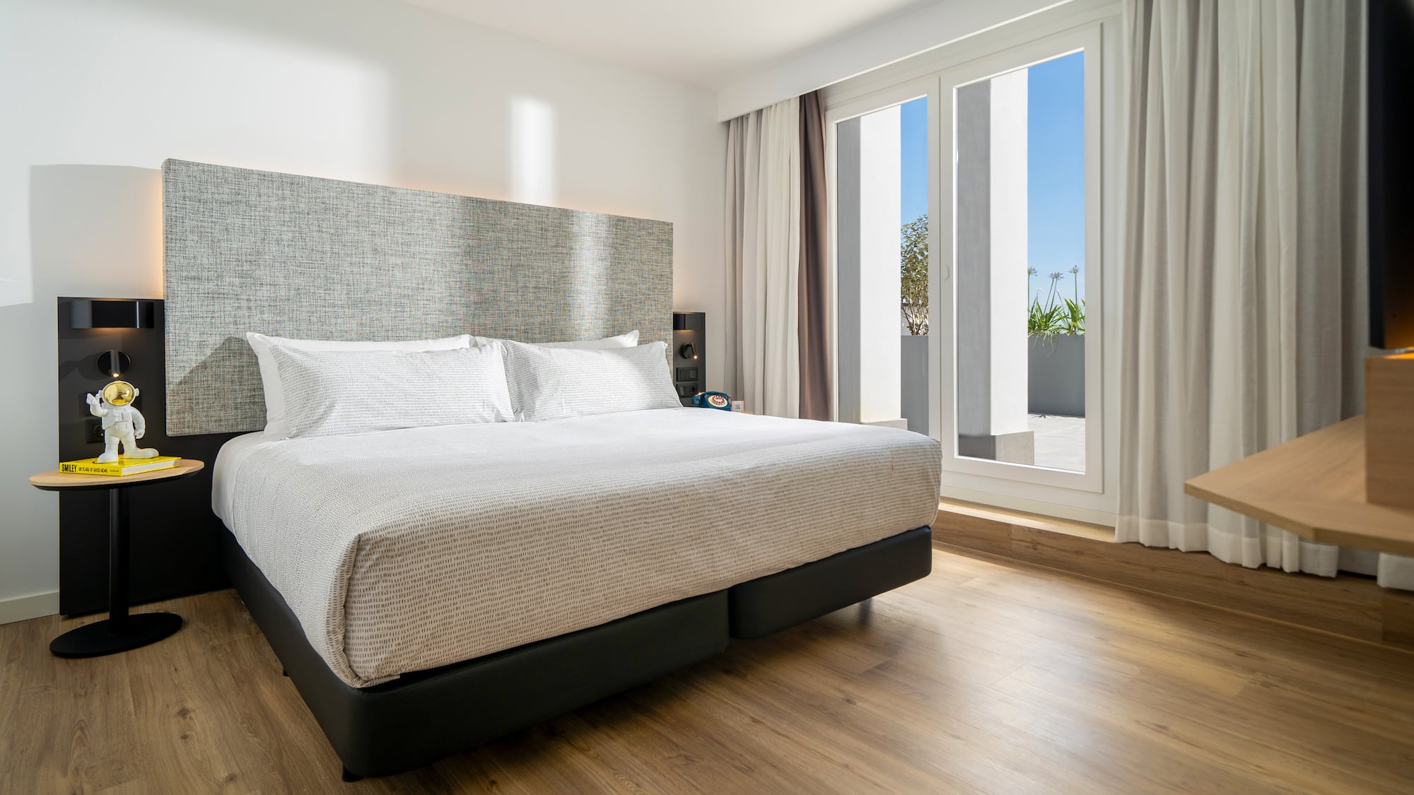 a bed in a room with a wood floor and windows