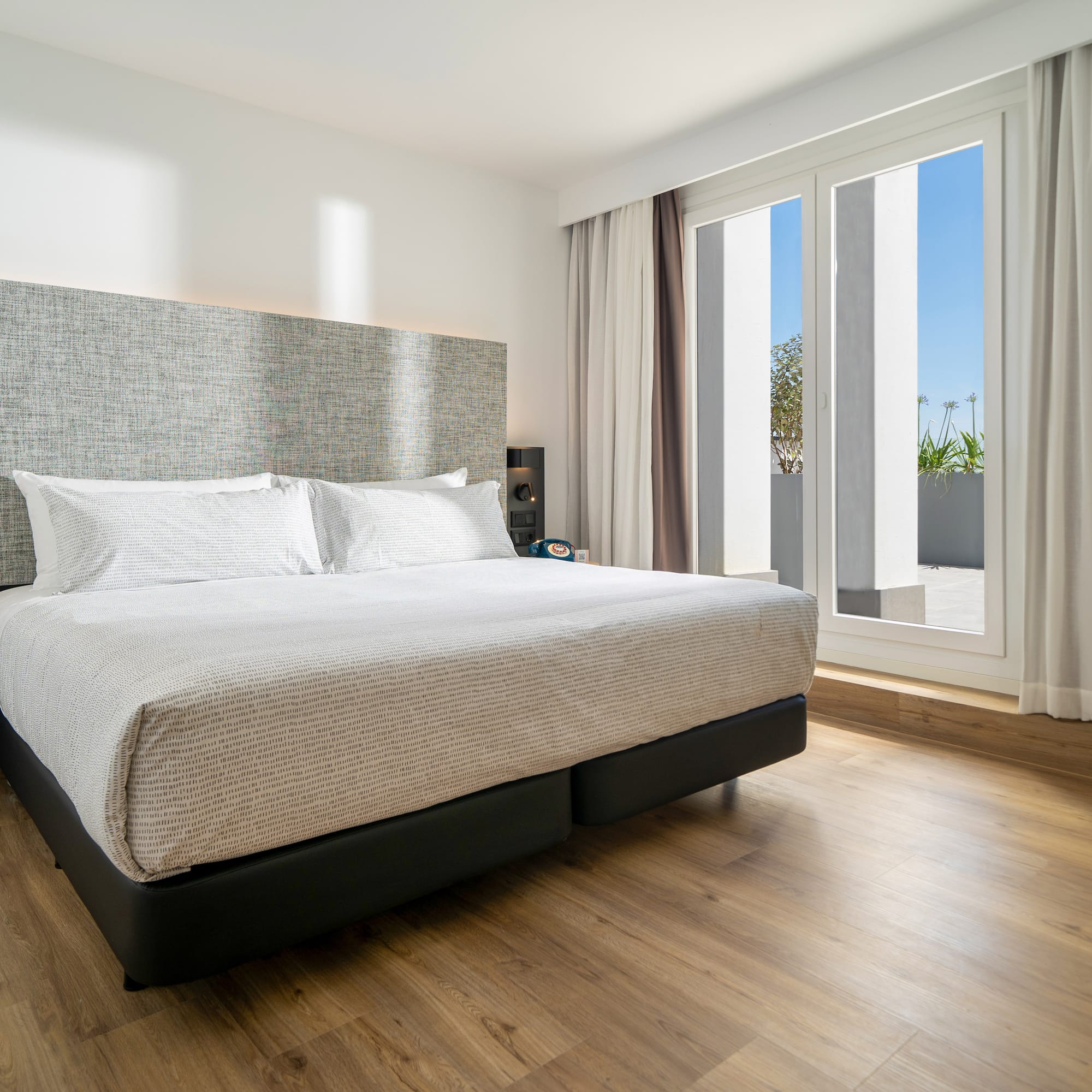a bed in a room with a wood floor and windows
