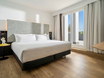 a bed in a room with a wood floor and windows