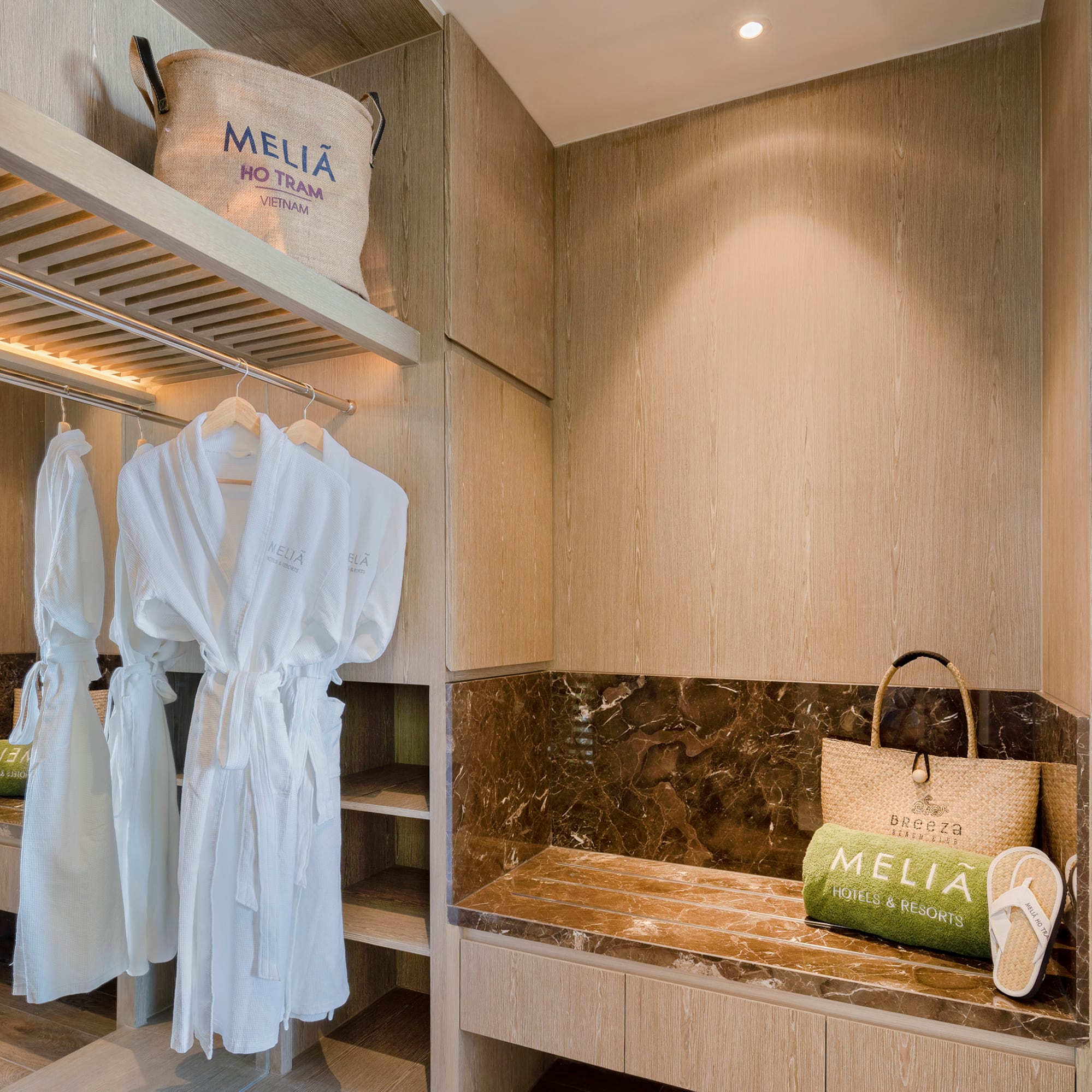 a room with white bathrobes and a bench