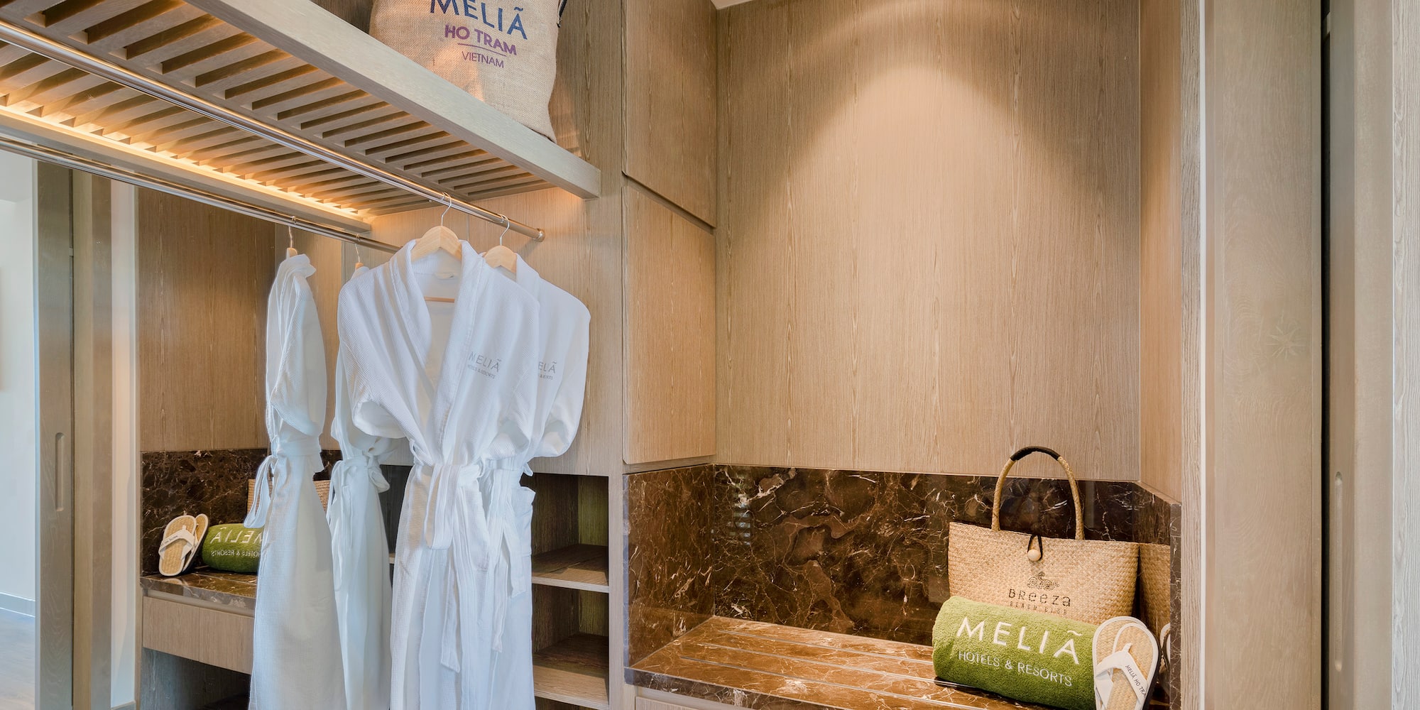 a room with white bathrobes and a bench