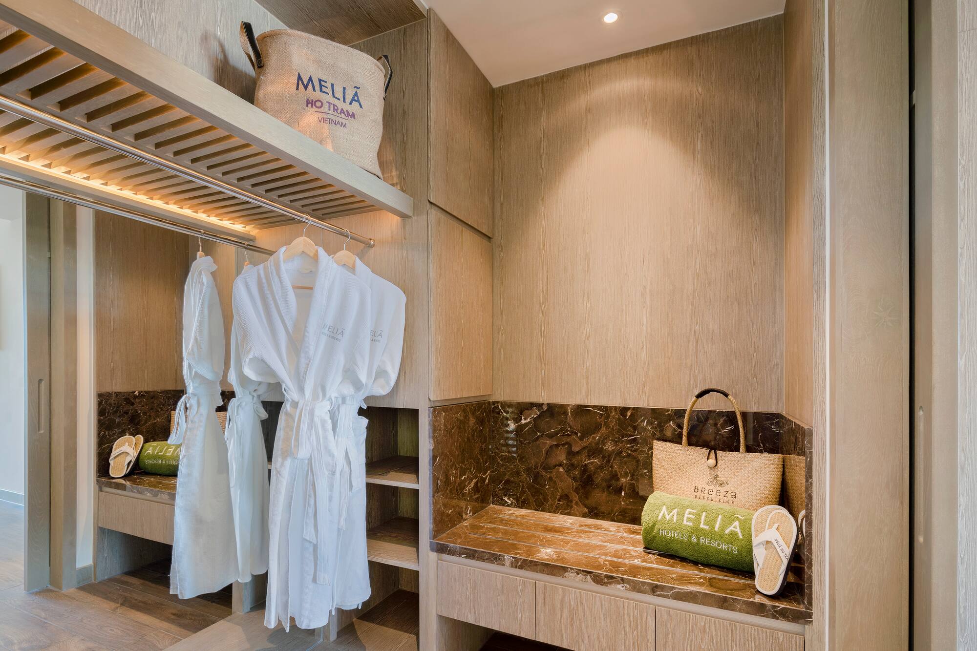 a room with white bathrobes and a bench
