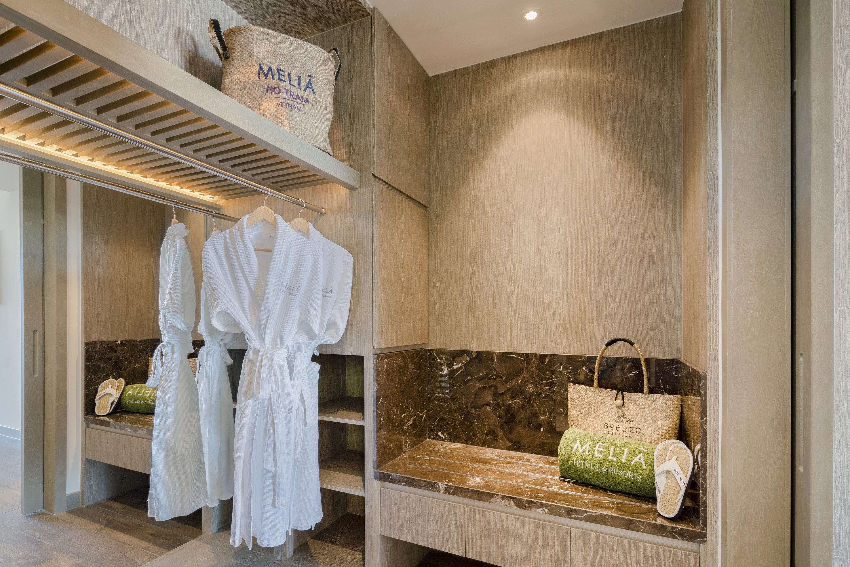 a room with white bathrobes and a bench