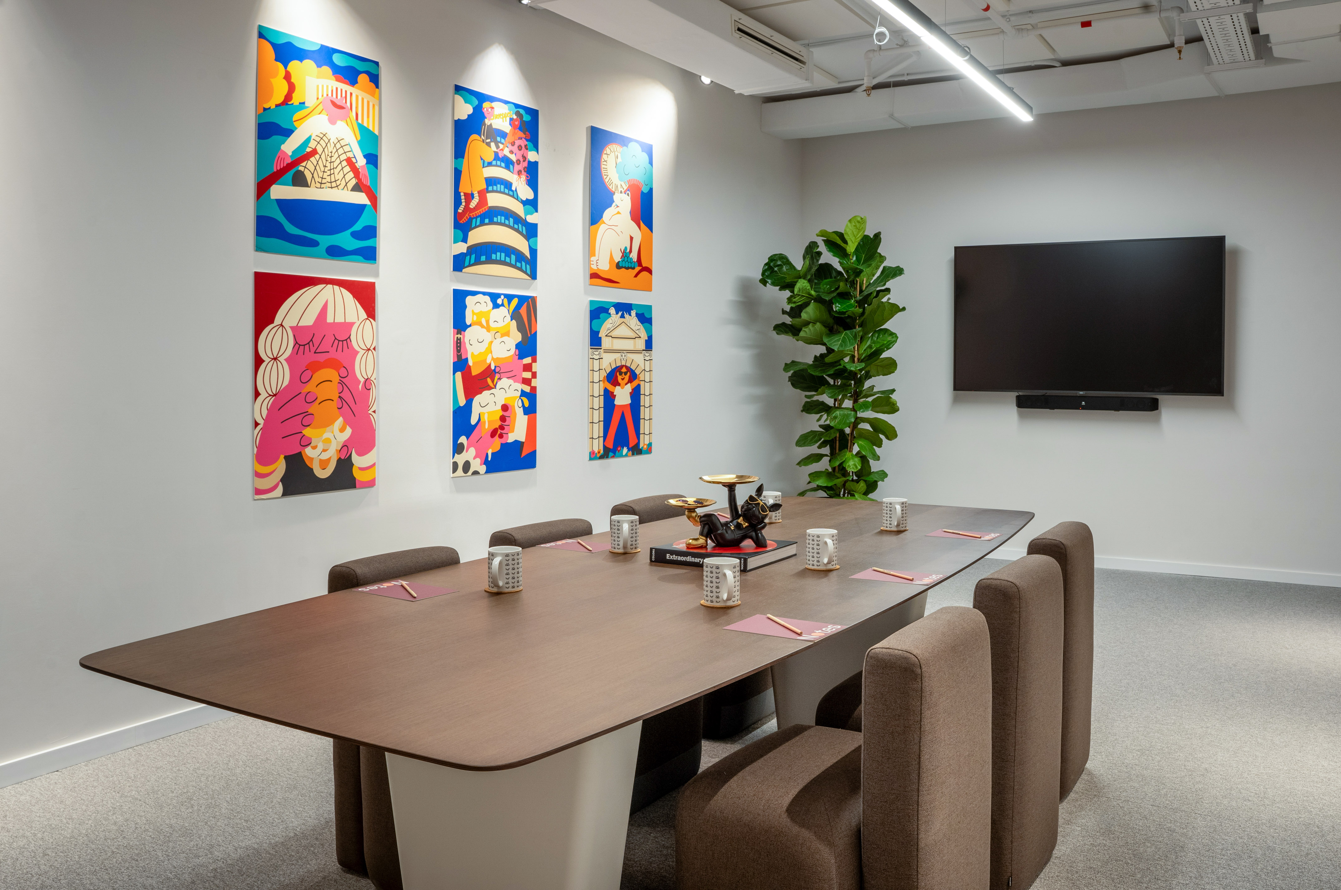Modern meeting room with colorful abstract art, long table, and TV.