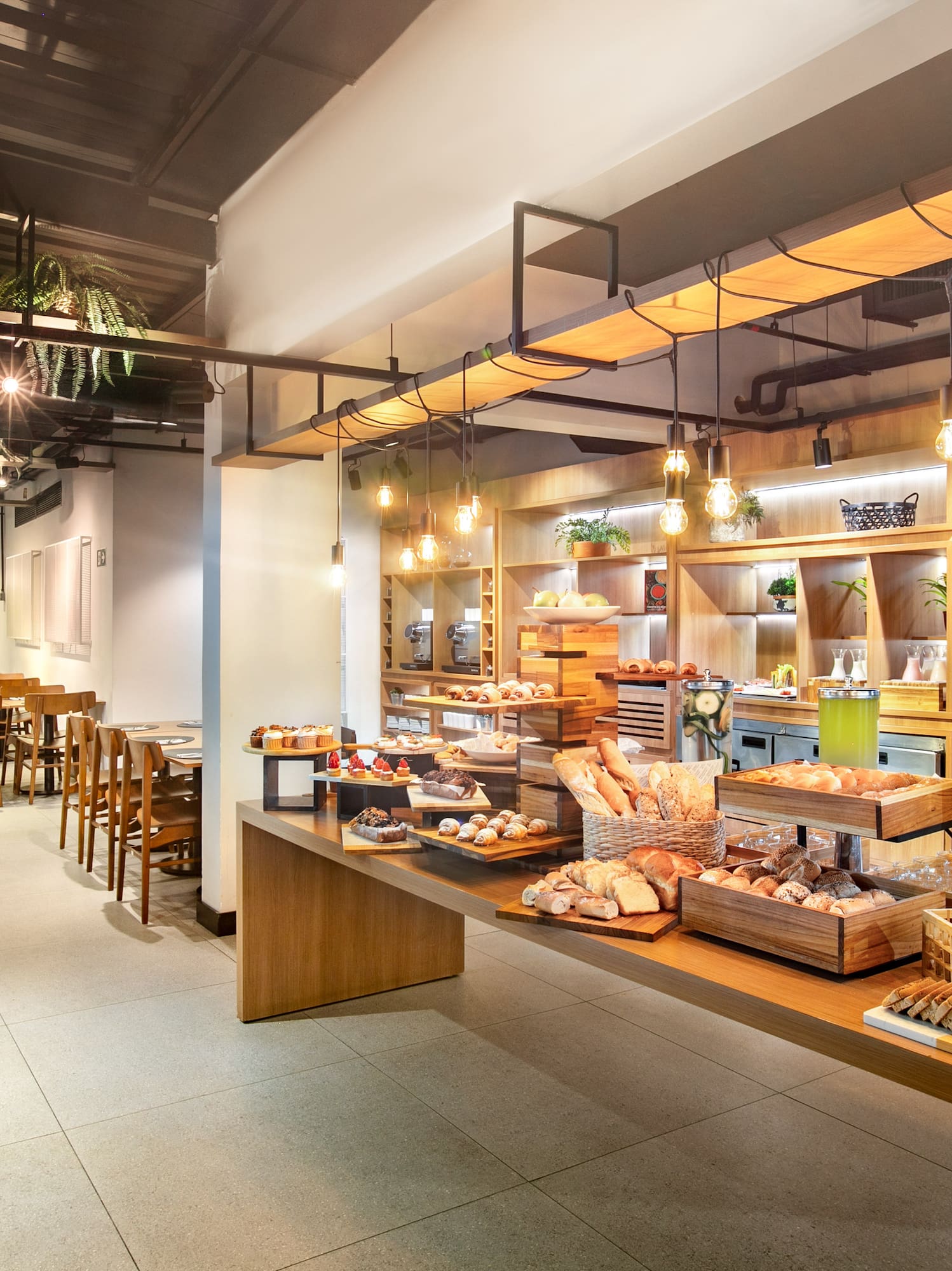 Hotel restaurant breakfast buffet with pastries, bread, and juices.