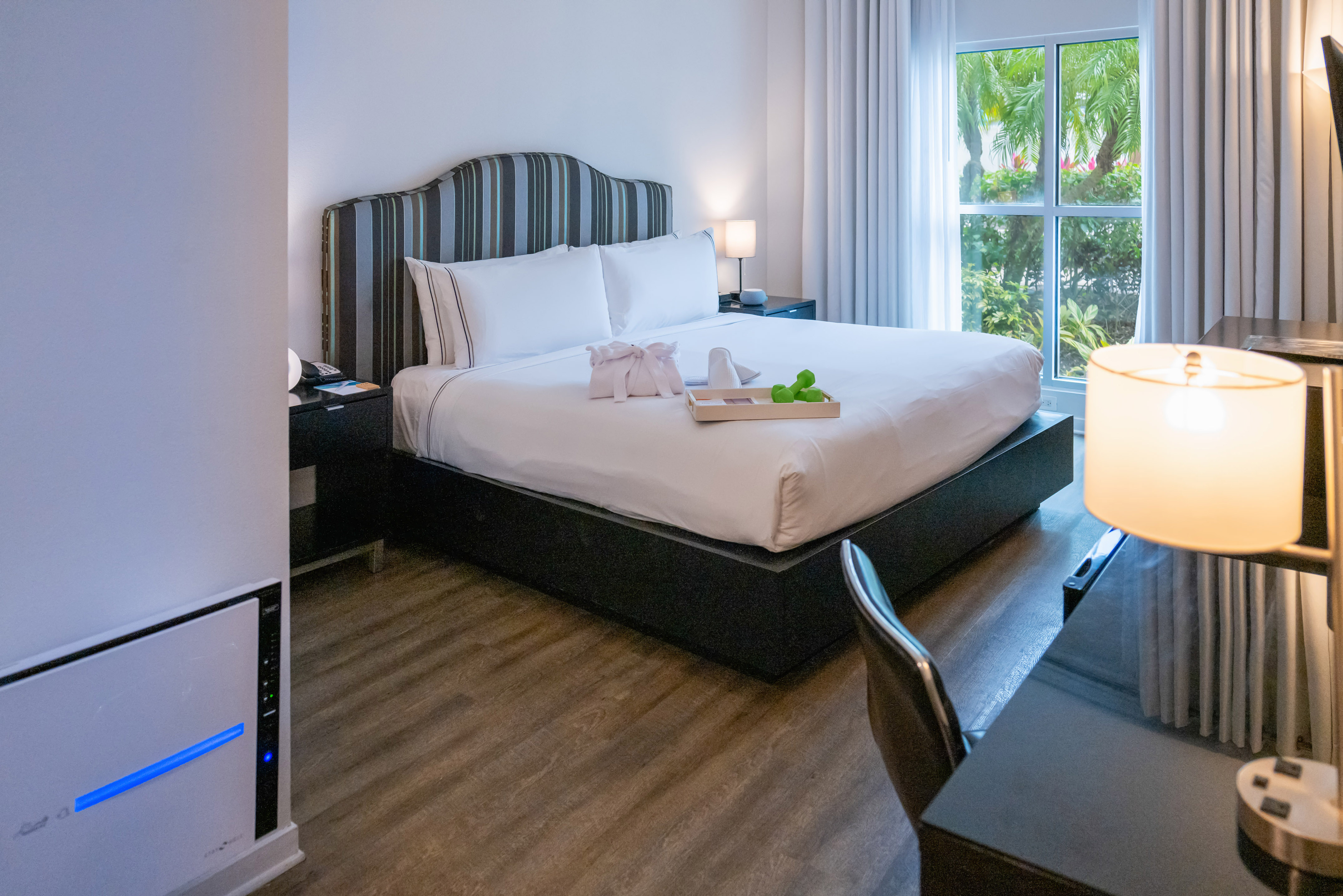 Modern hotel bedroom with king bed, striped headboard, and tropical window view. - The Level Two Bedroom Suite - Meliá Orlando Celebration, Orlando