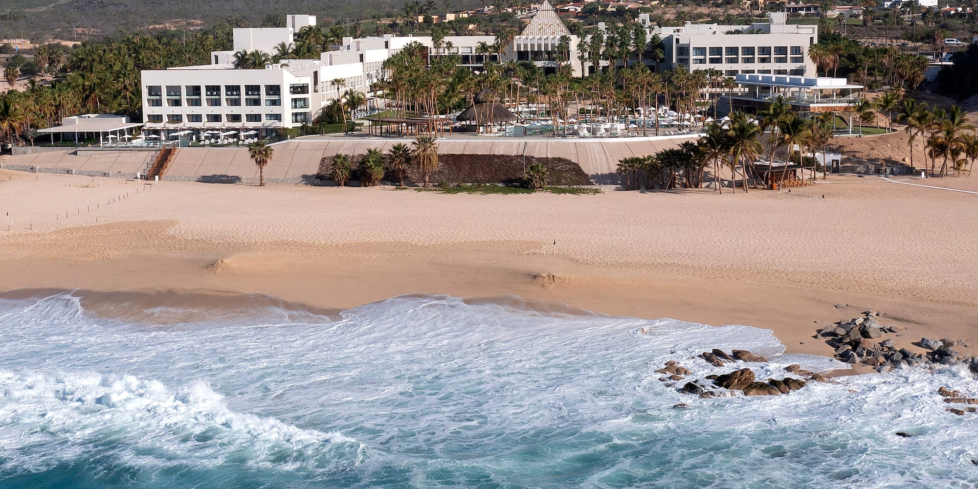 Tropical resort with sandy beach and turquoise ocean waves.