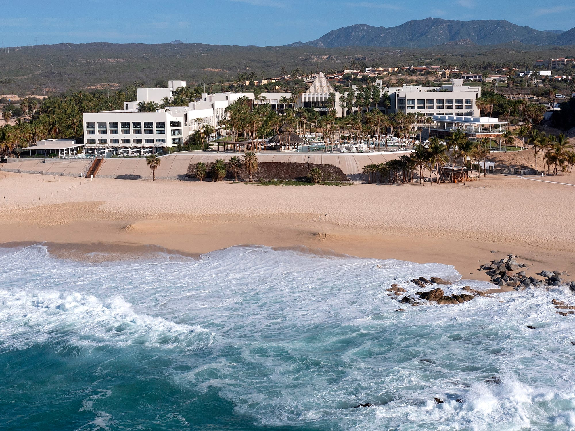 Tropical resort with sandy beach and turquoise ocean waves.