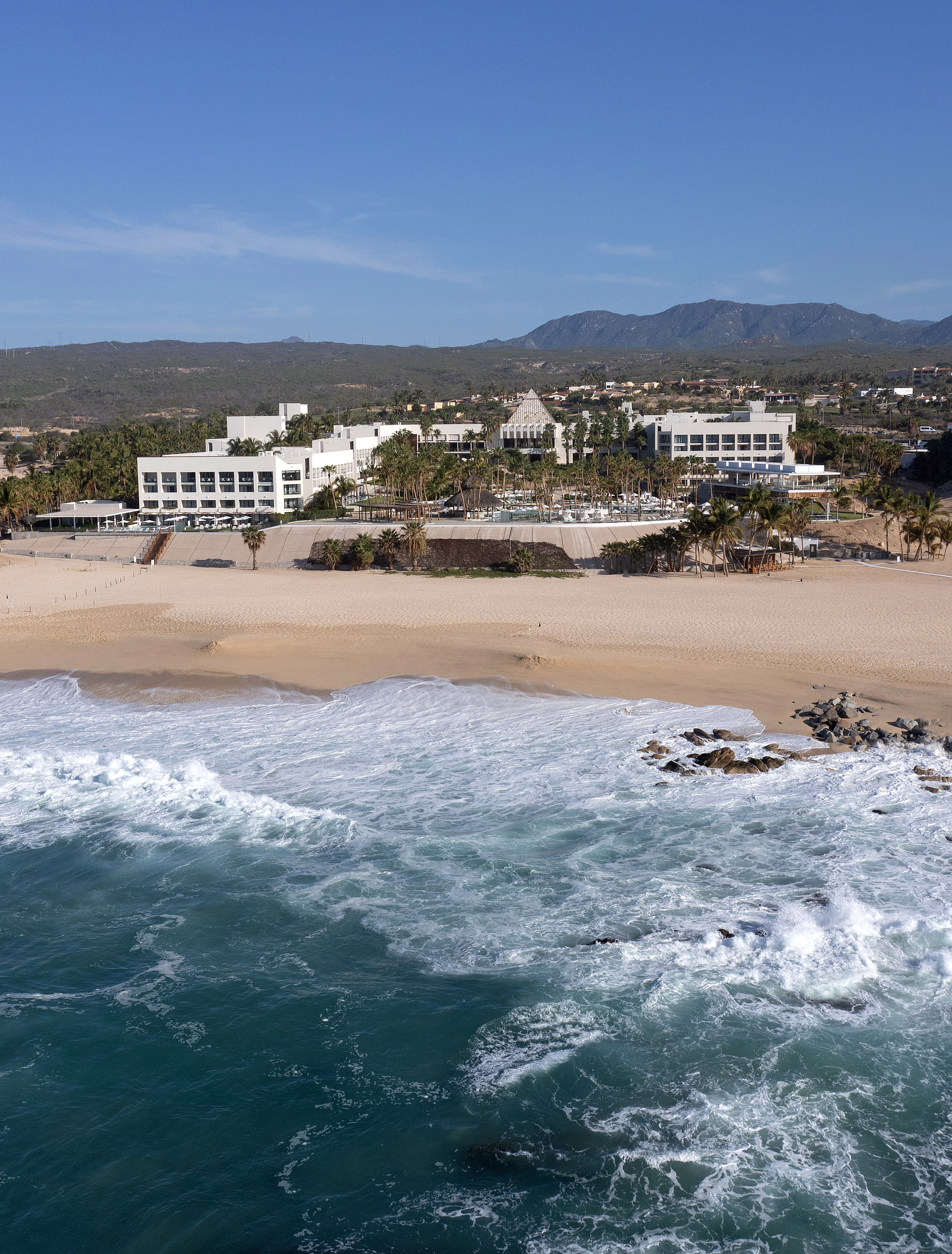 Tropical resort with sandy beach and turquoise ocean waves.