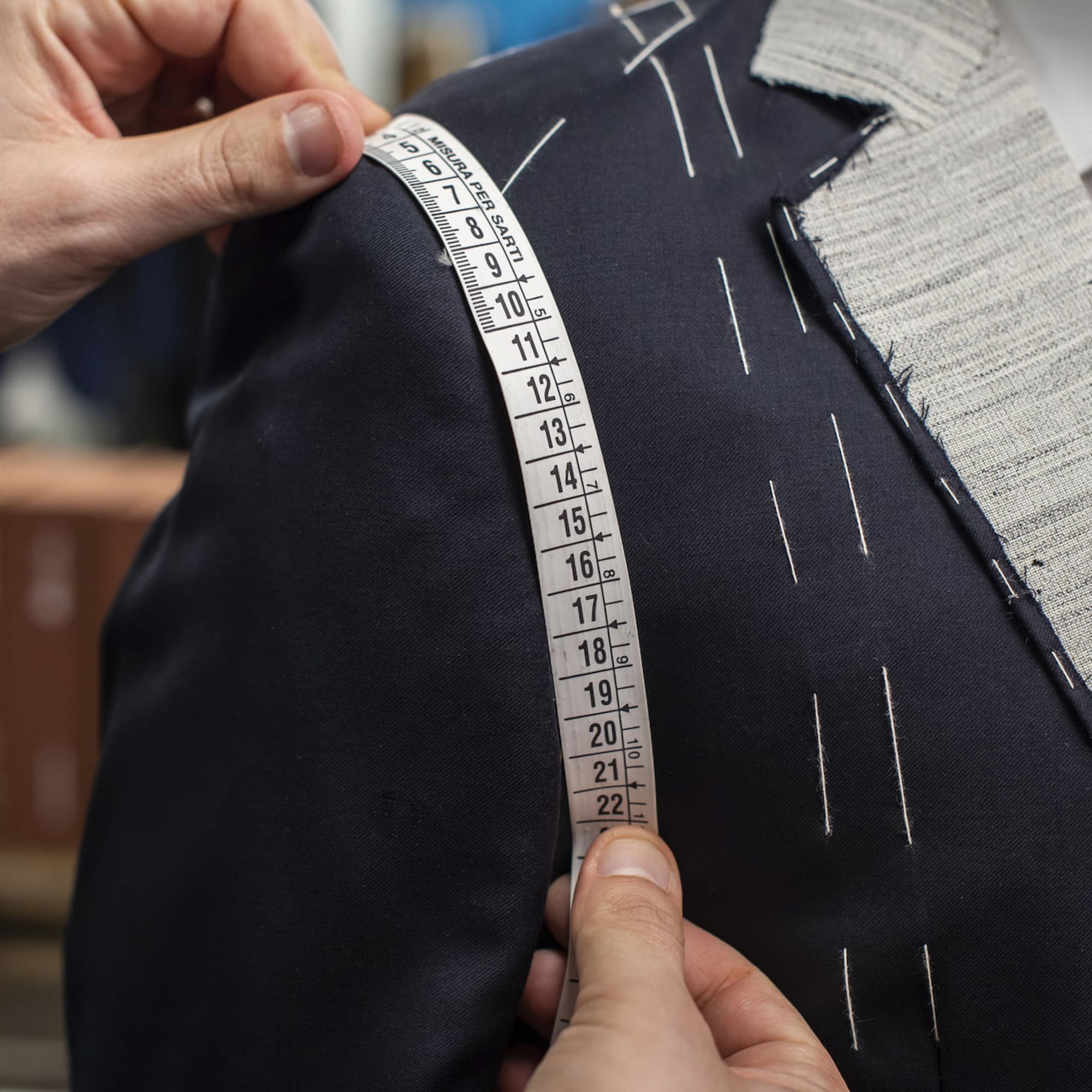 a person measuring a suit