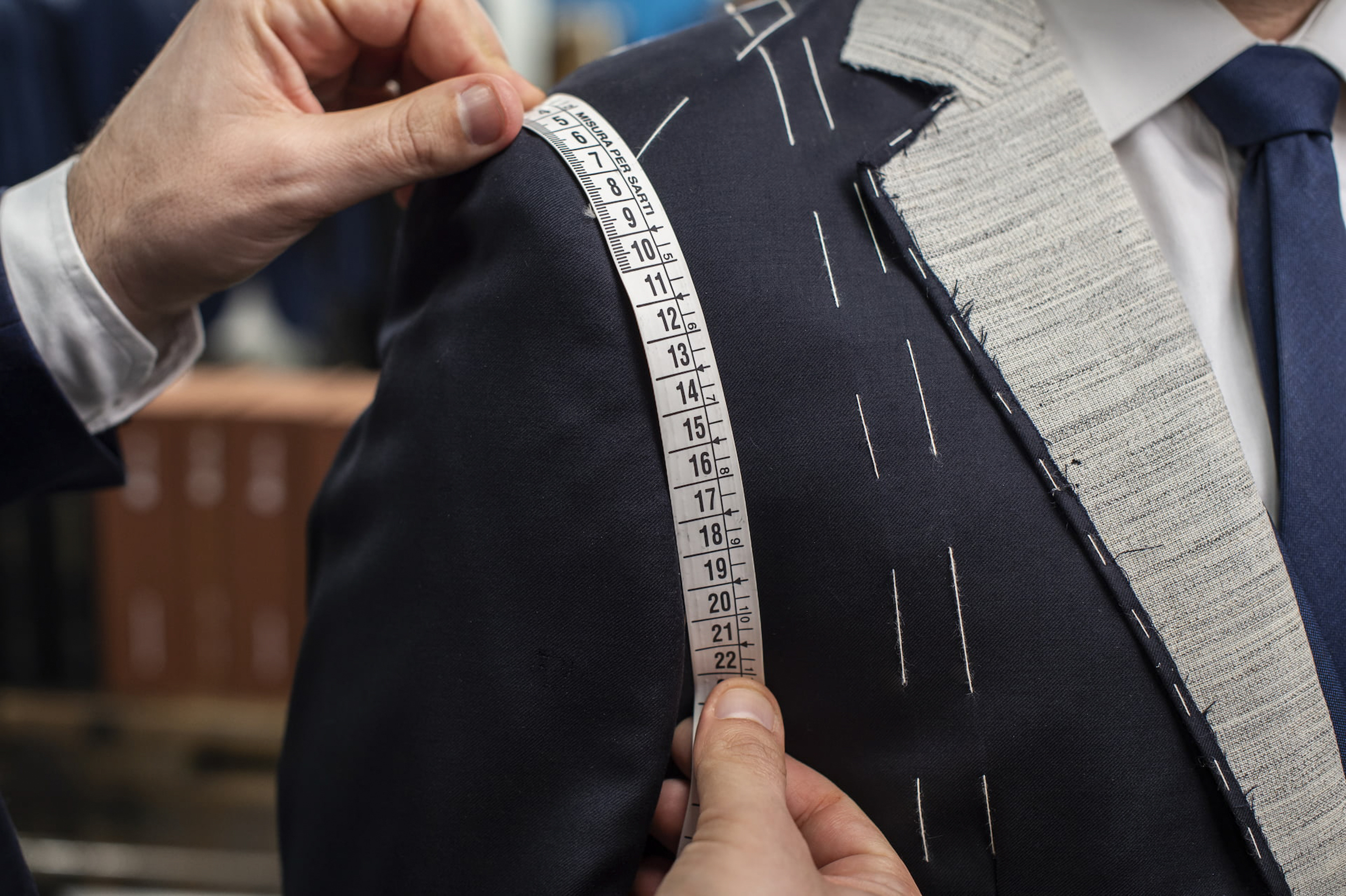a person measuring a suit