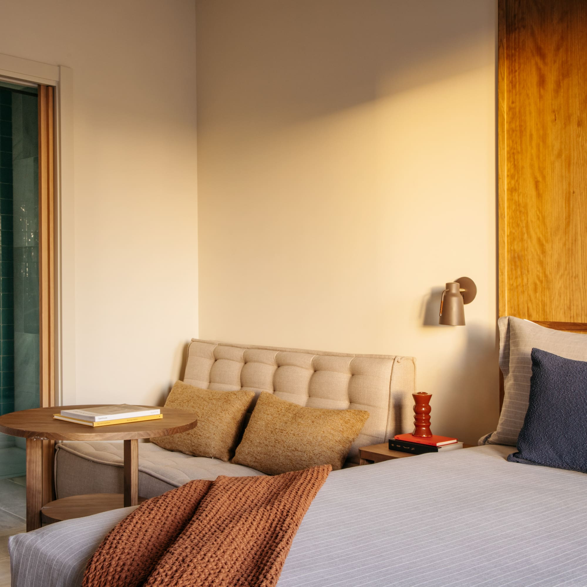 Modern hotel bedroom with turquoise shower and wood accents.
