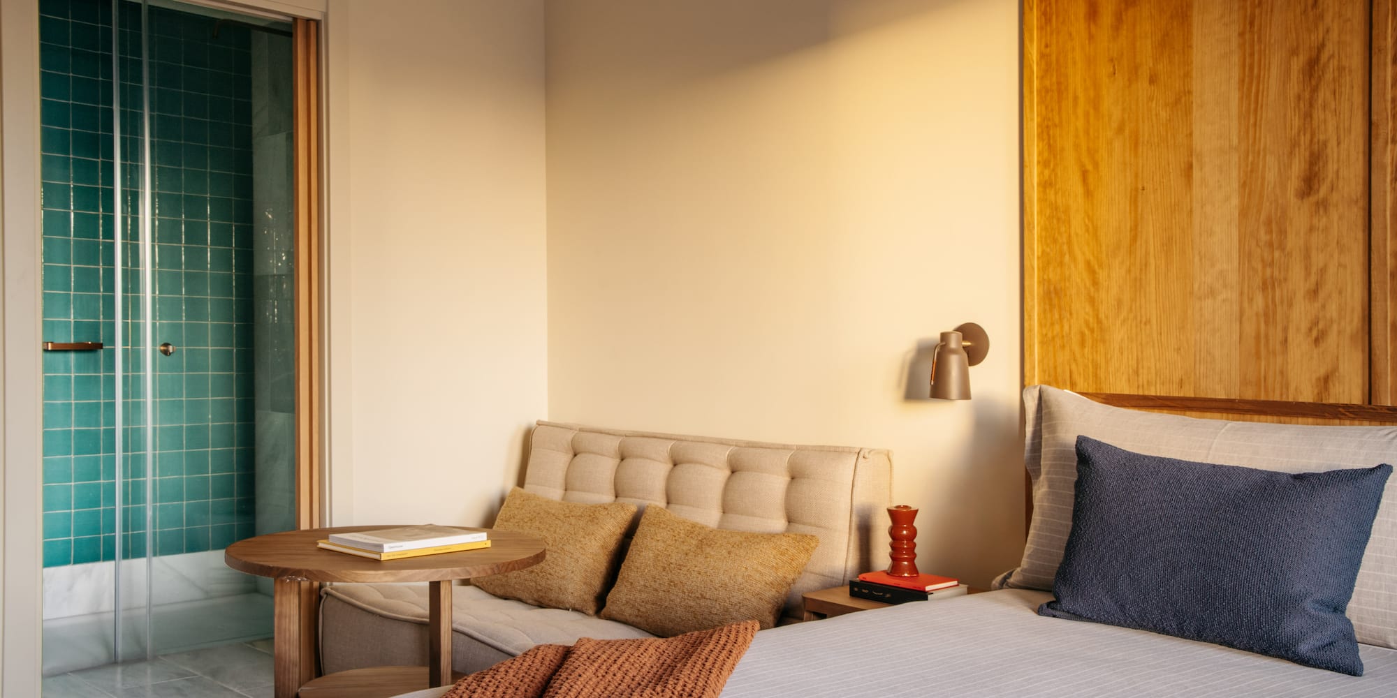 Modern hotel bedroom with turquoise shower and wood accents.
