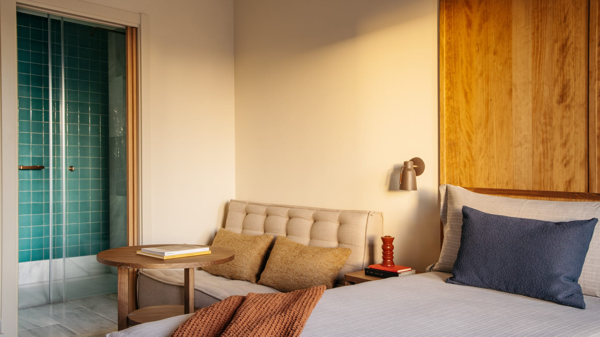 Modern hotel bedroom with turquoise shower and wood accents.