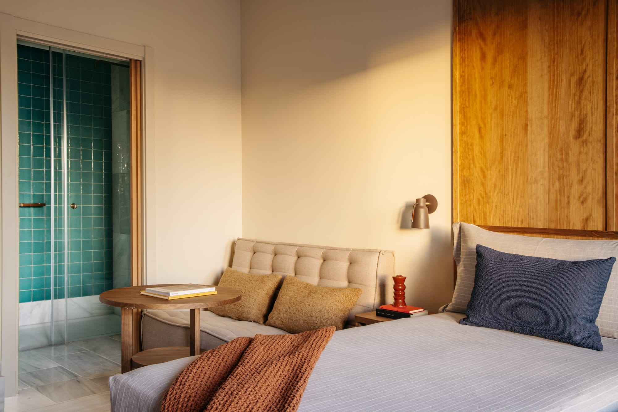 Modern hotel bedroom with turquoise shower and wood accents.