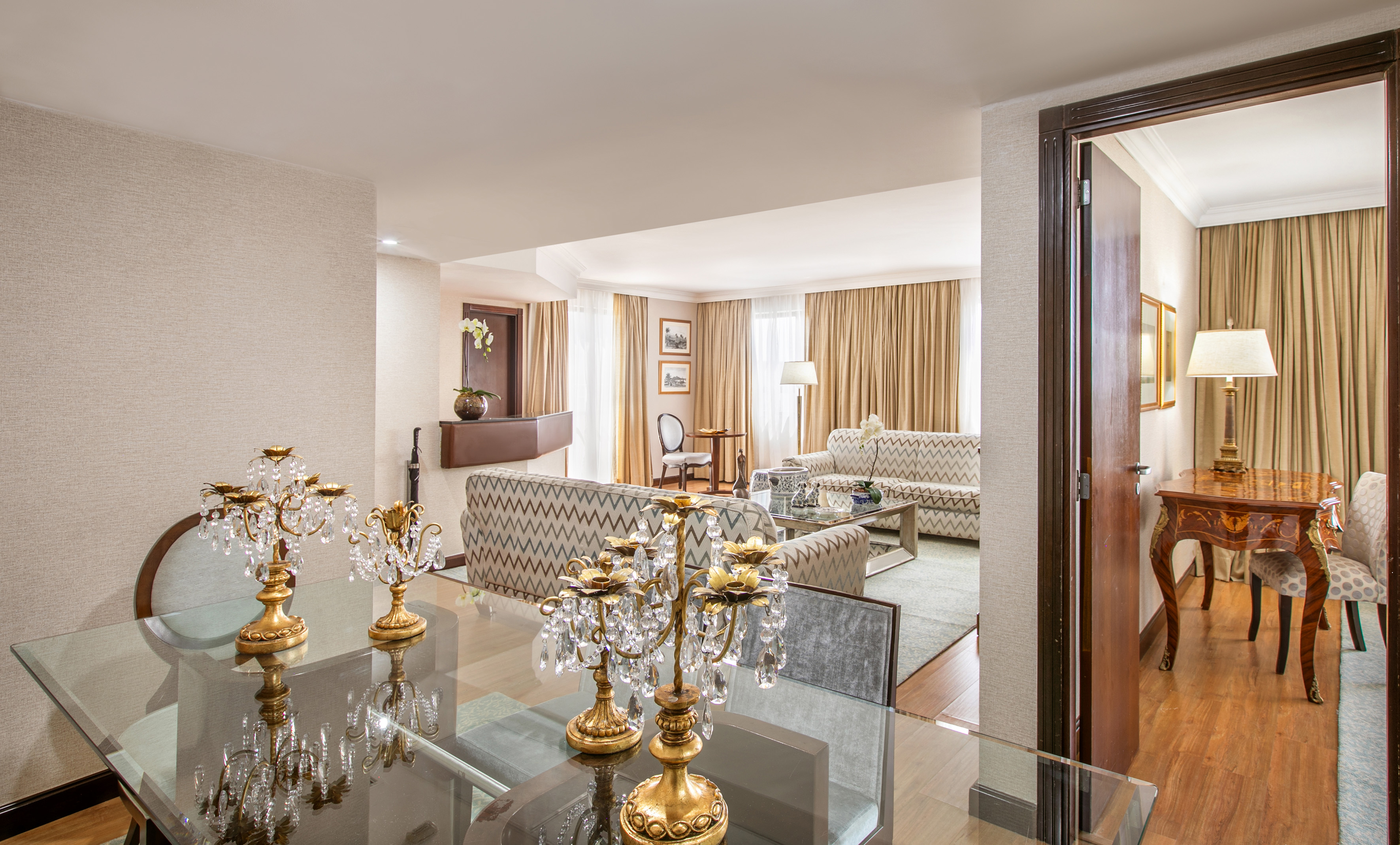 Elegant hotel suite living room with gold candelabras and patterned sofas.