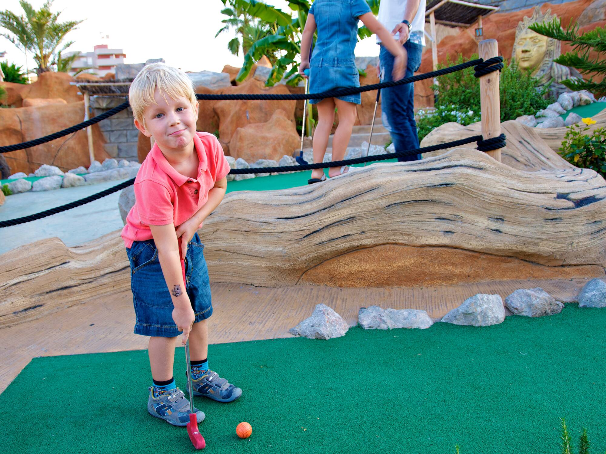 a boy playing golf with a golf ball