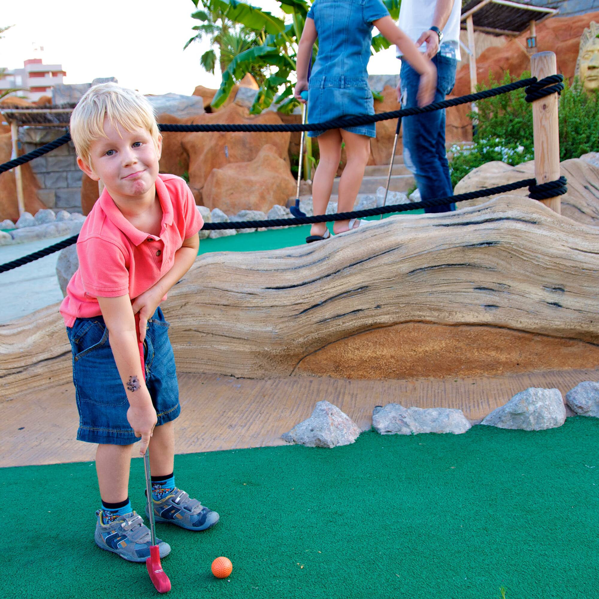 a boy playing golf with a golf ball