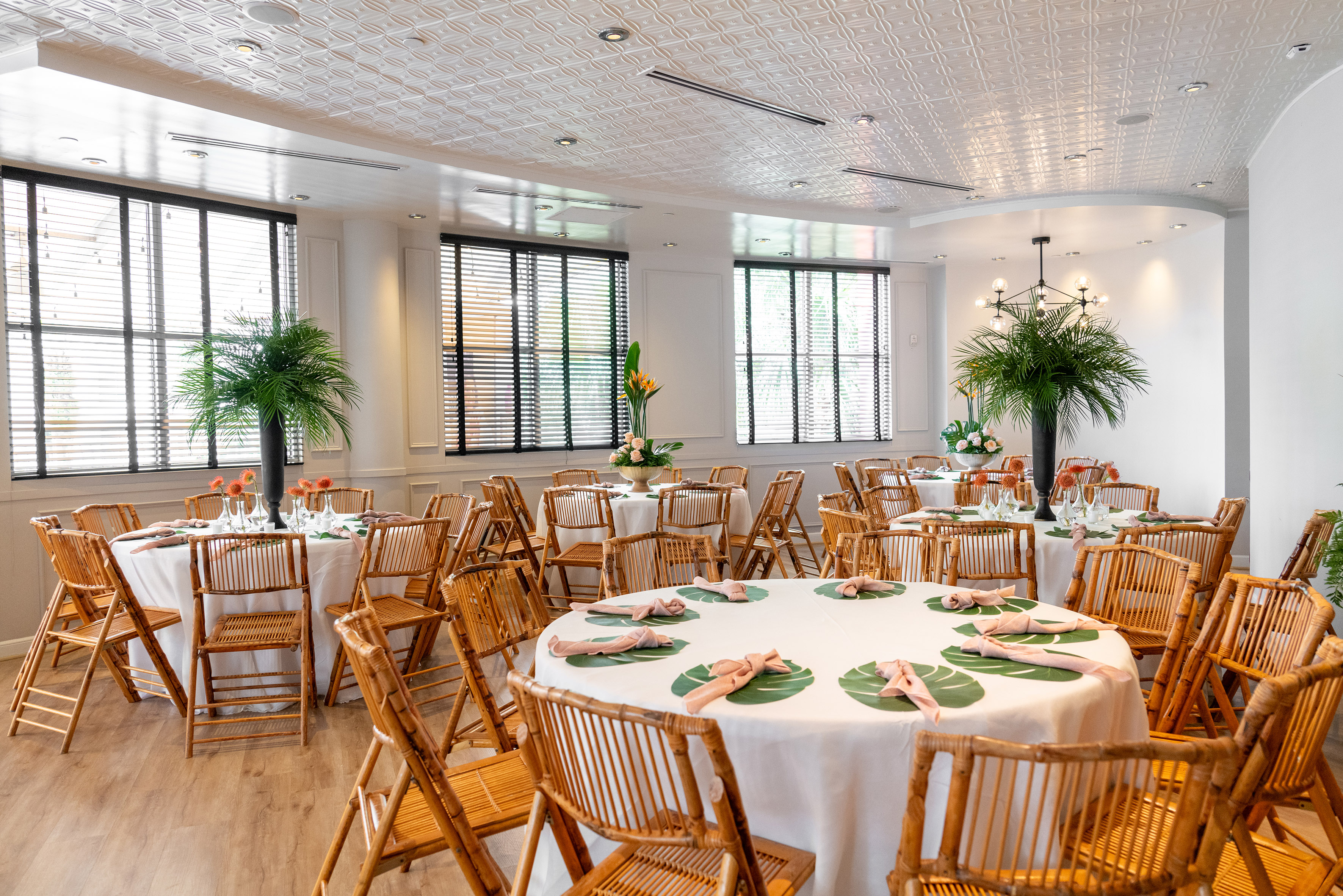 Banquet room with tropical bamboo chairs, white tables, and palm decor. - The Pearl (circular floor plan) - Meliá Orlando Celebration, Orlando