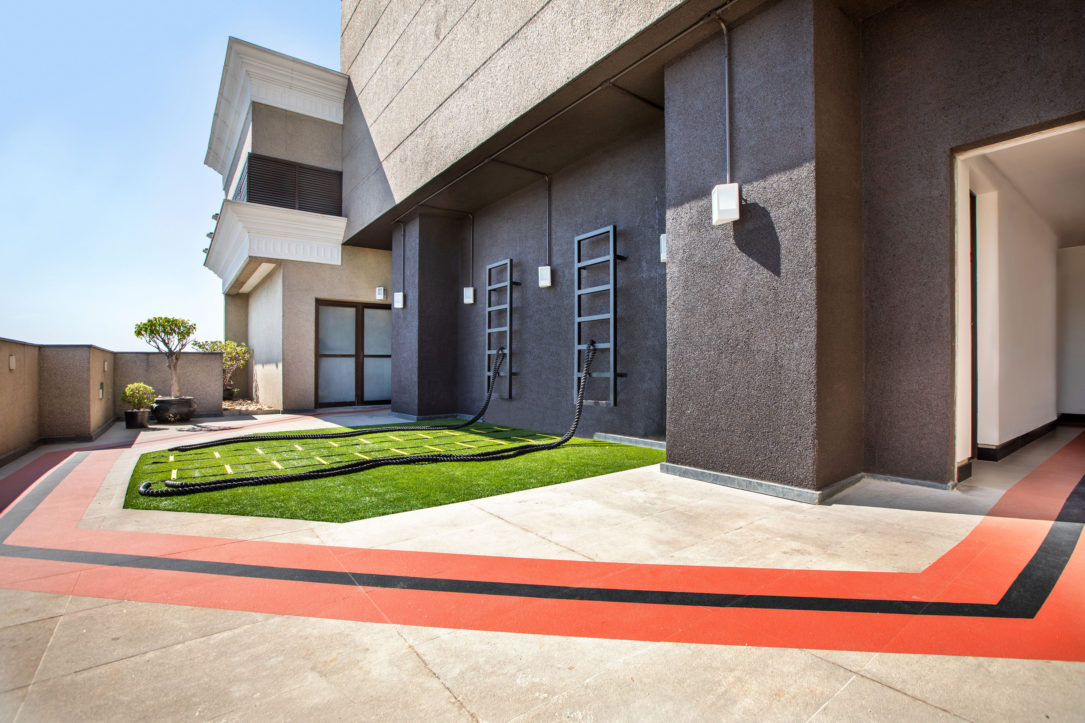 Outdoor gym terrace with battle ropes, artificial turf, and agility markings.