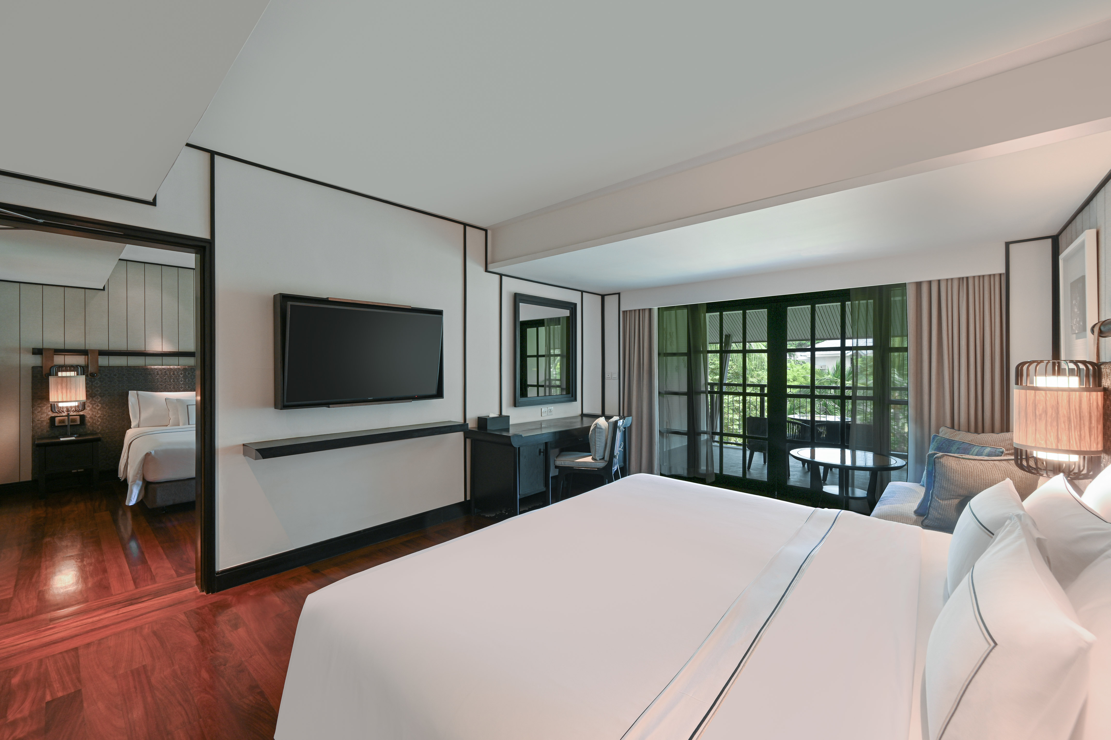 Modern hotel room with king bed, TV, desk, and private balcony access.