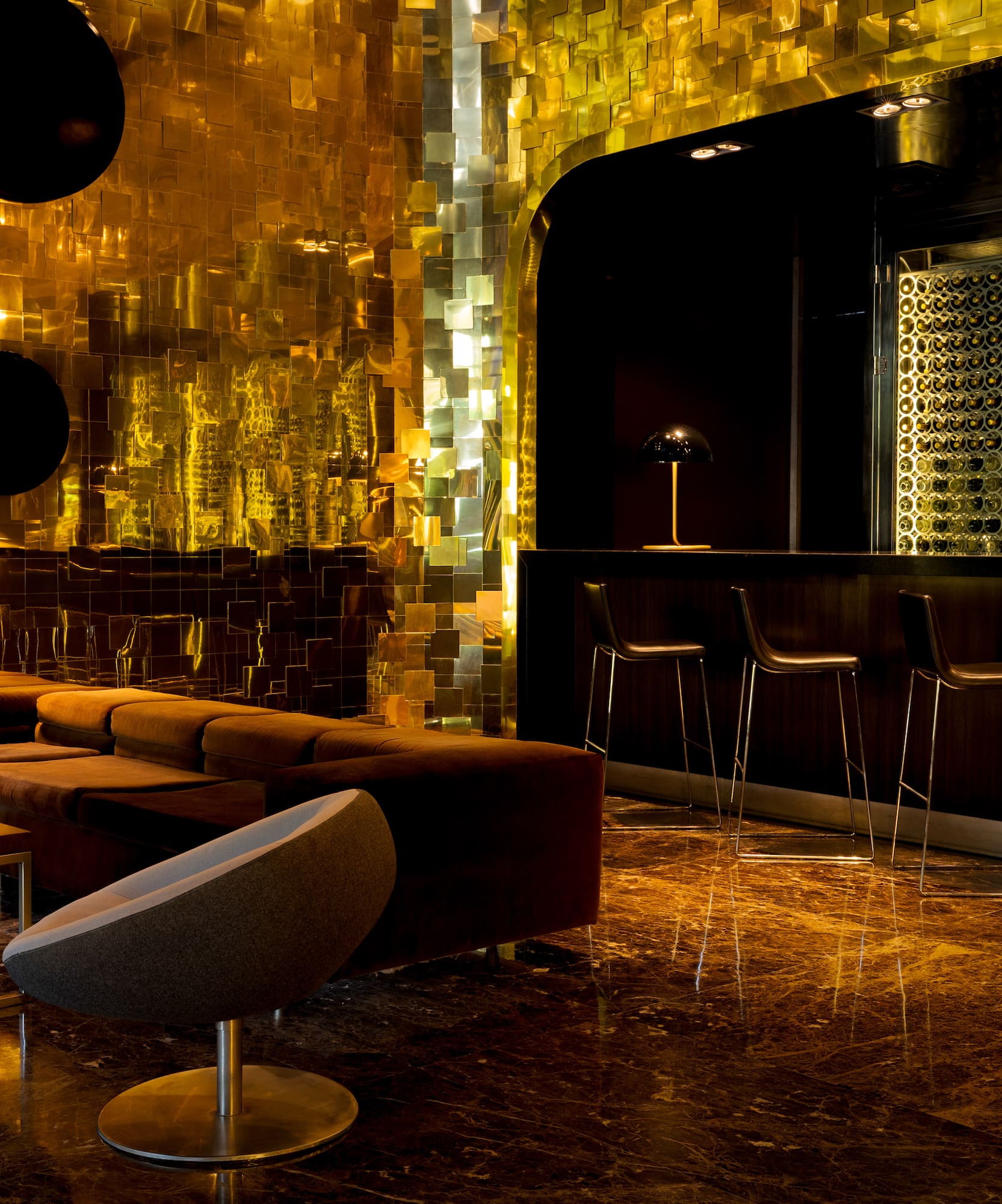 Luxury bar lounge with golden walls, wine display, and modern seating.