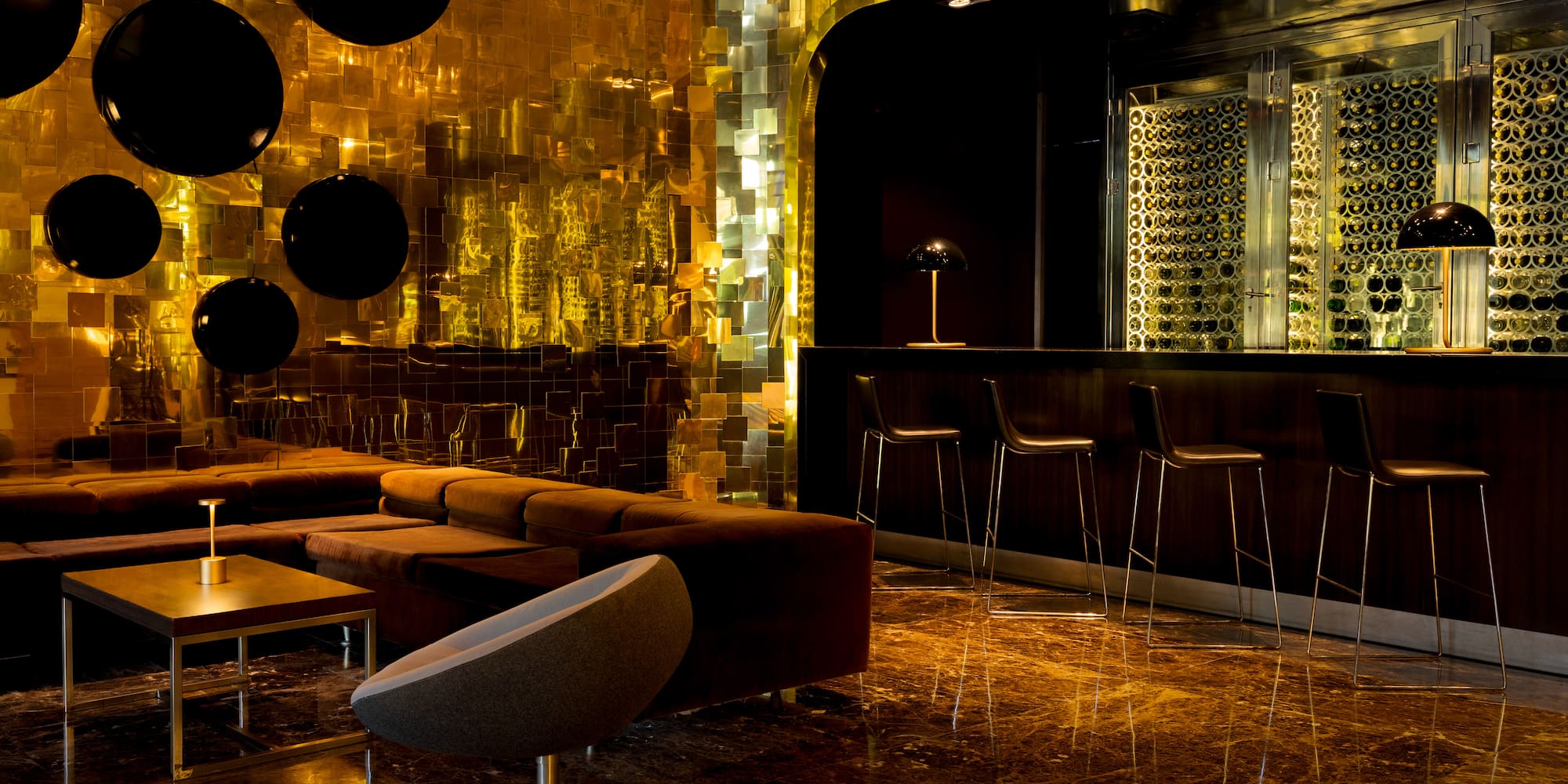 Golden-walled luxury bar with lounge seating and illuminated wine display.