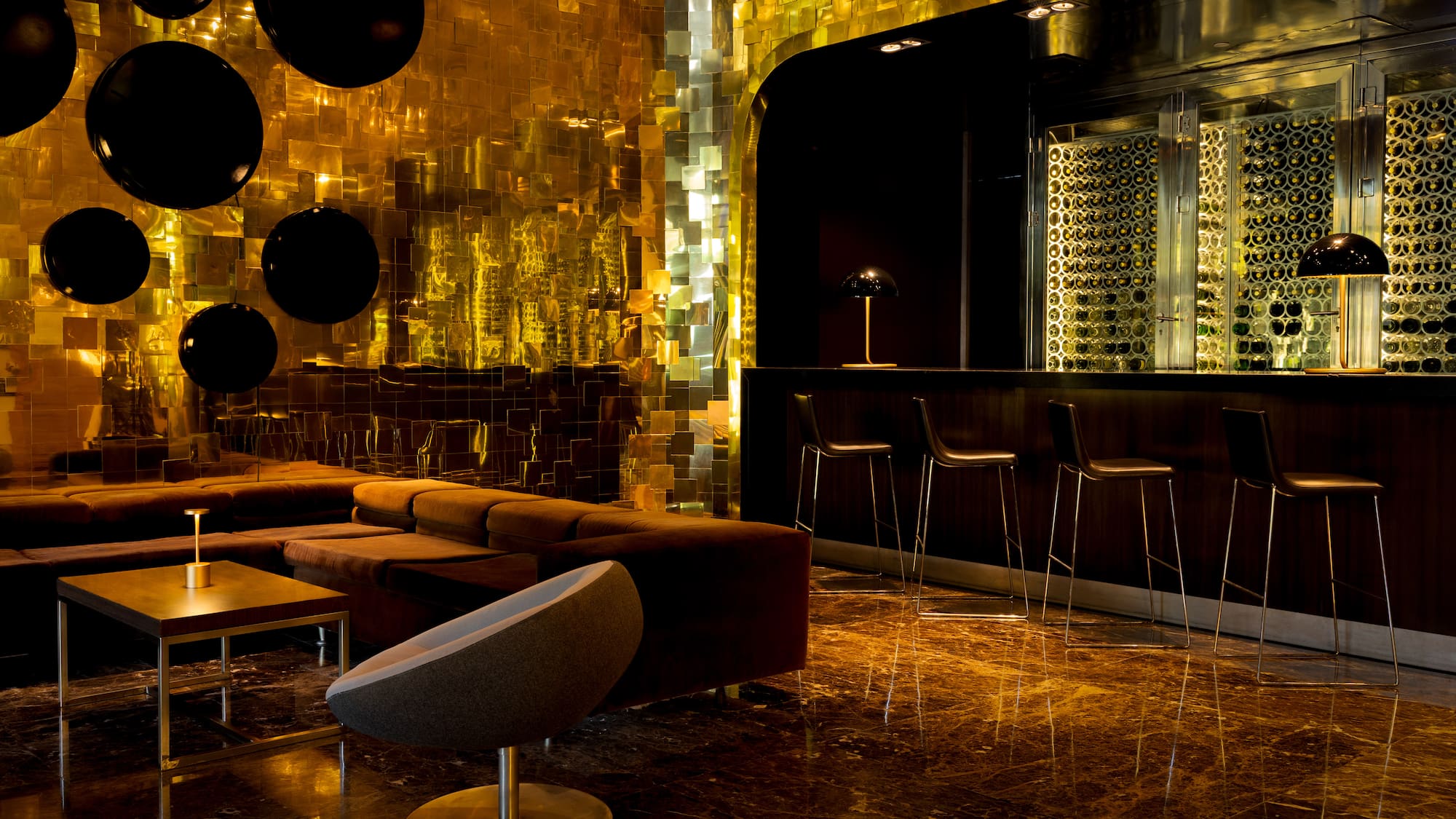 Golden-walled luxury bar with lounge seating and illuminated wine display.