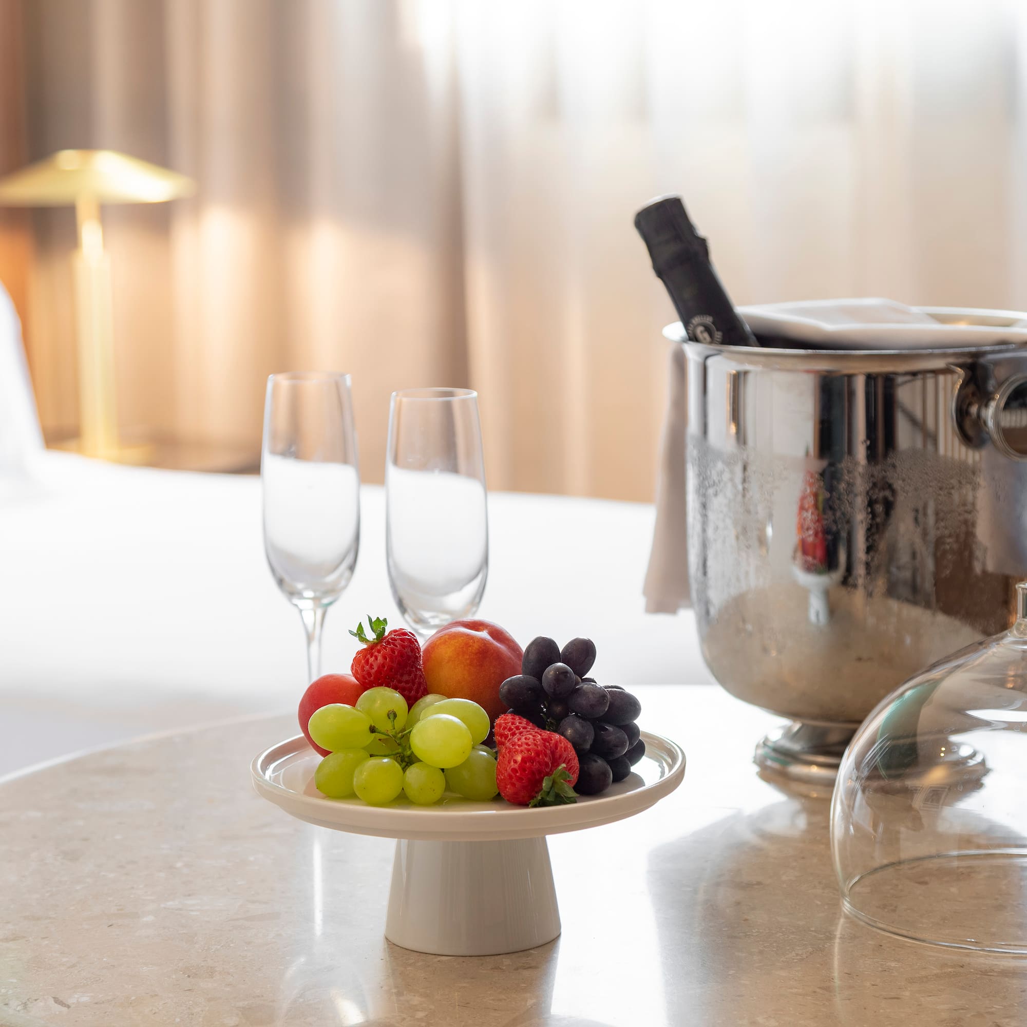 a plate of fruit and wine glasses on a table