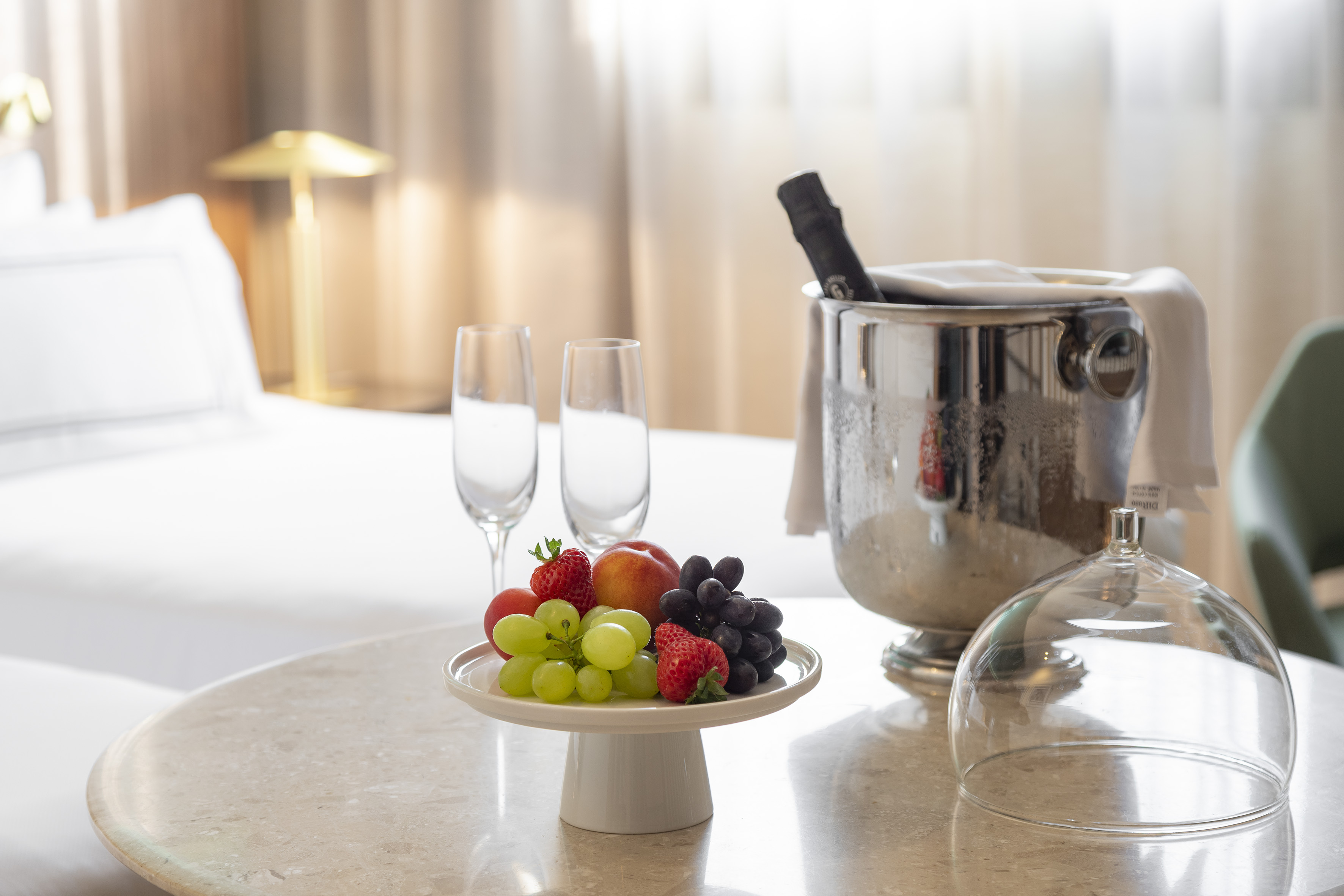 Hotel room welcome amenity with fresh fruit, champagne, and flutes.