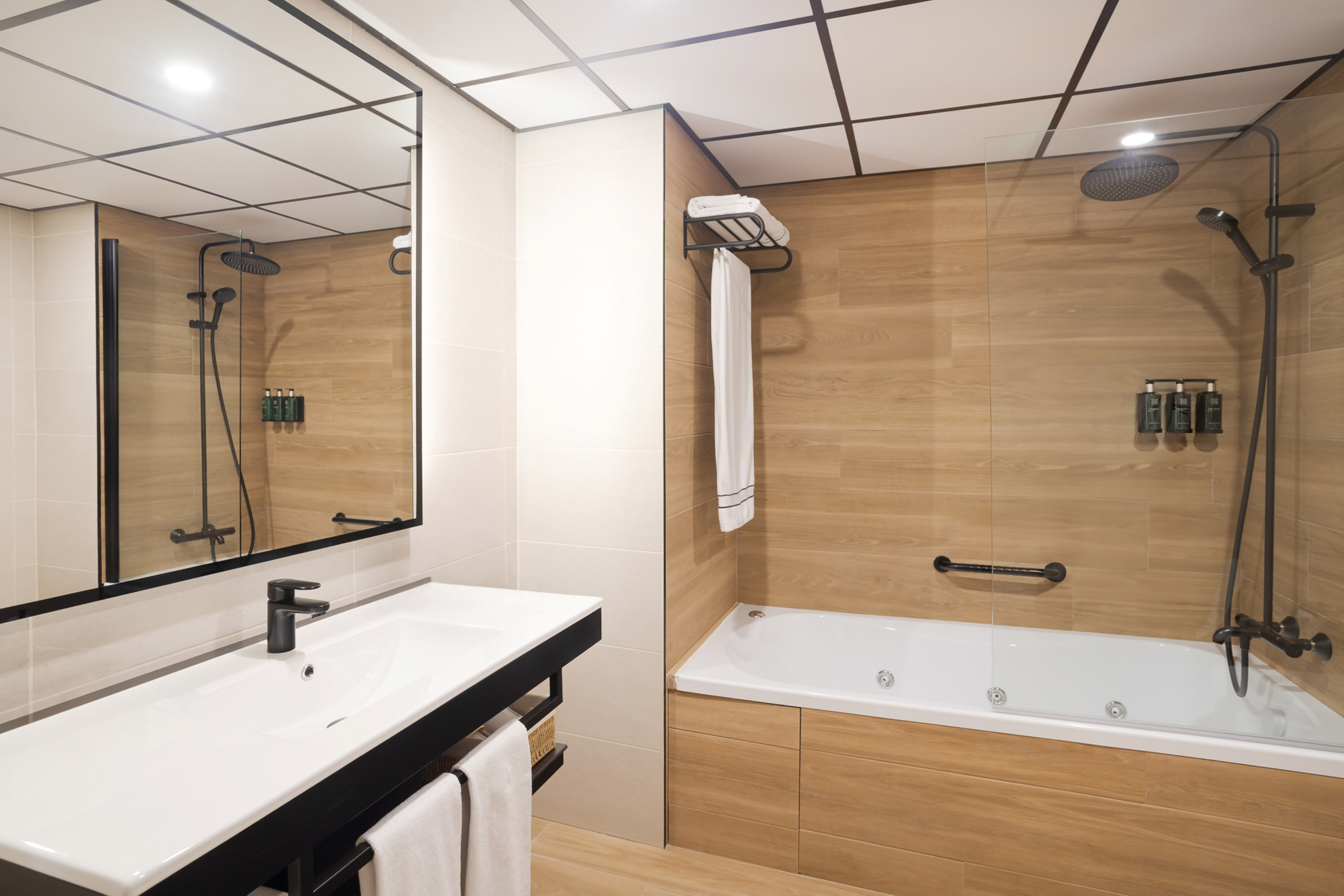 Modern bathroom with wood-look tiles, sink, mirror, shower, and jetted tub.