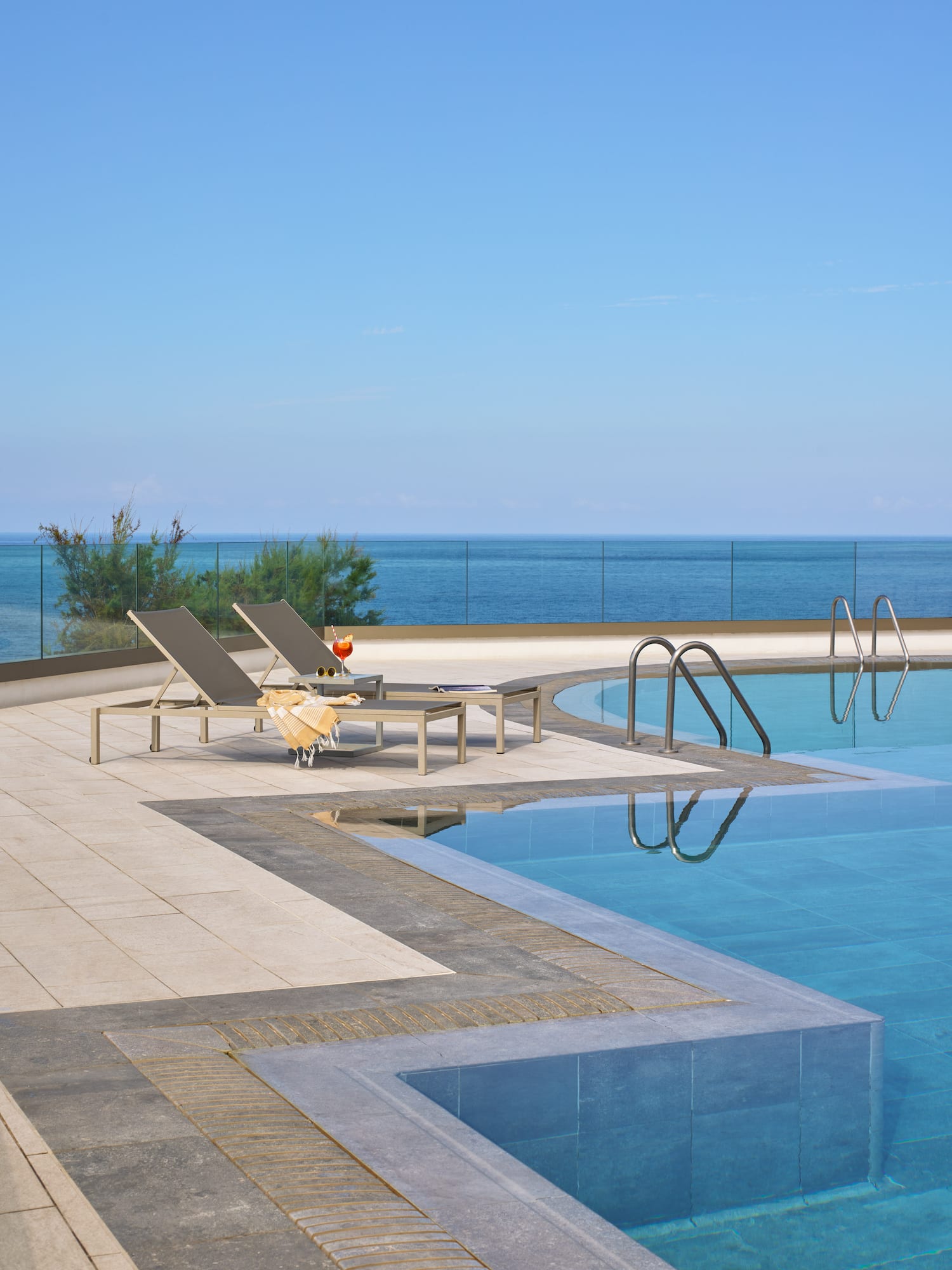 a pool with chairs and a glass of wine on the side