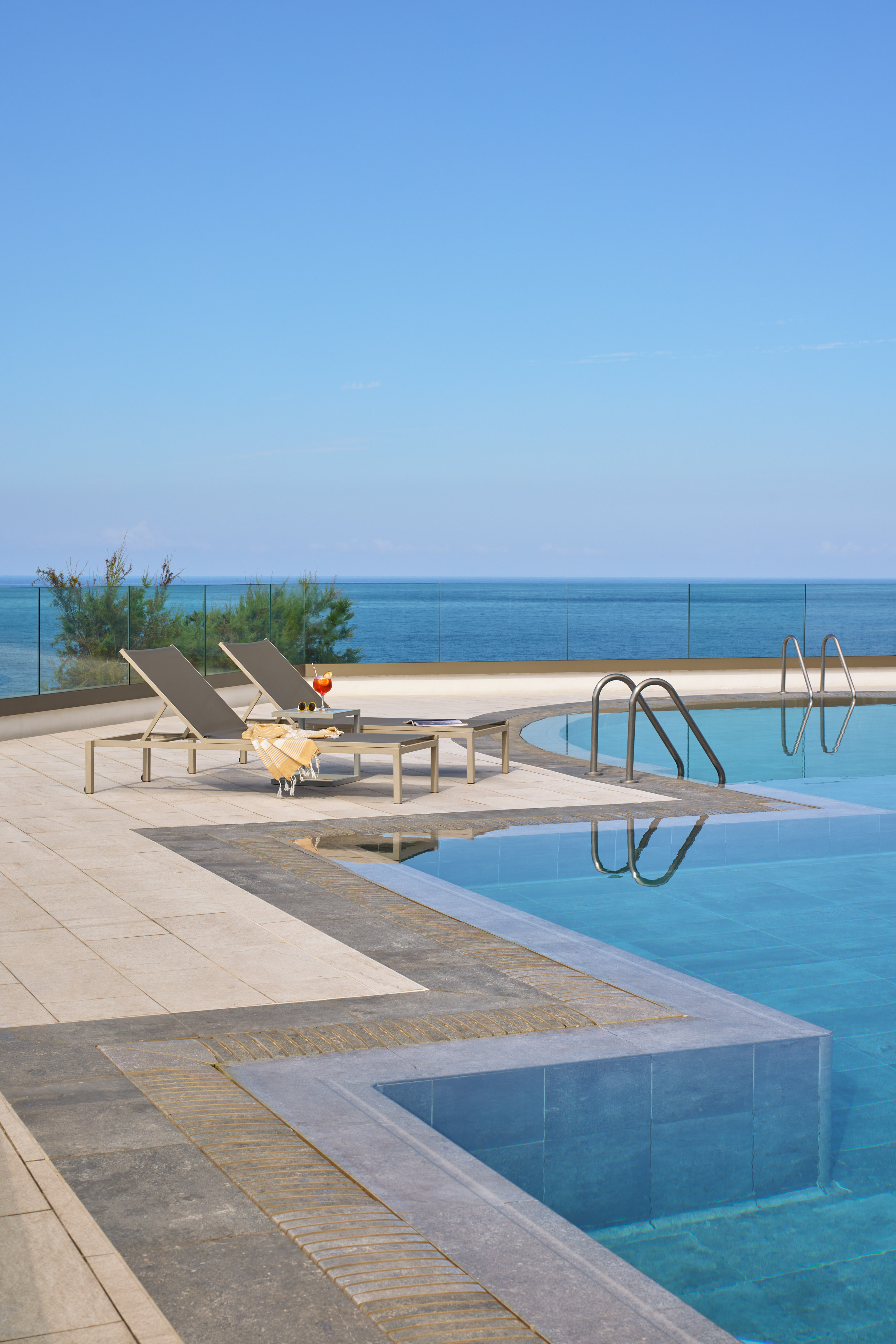 a pool with chairs and a glass of wine on the side