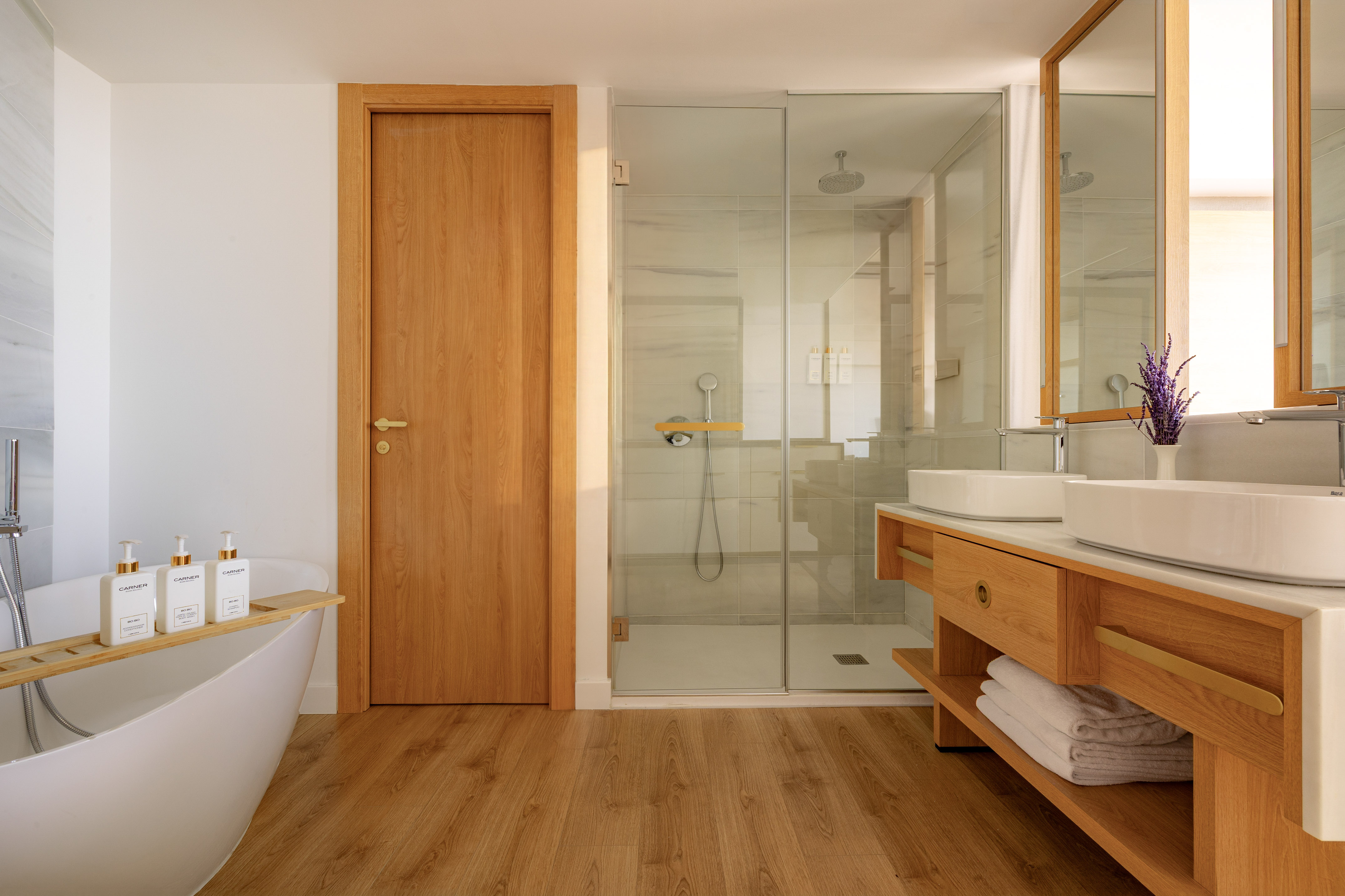 Elegant bathroom with freestanding tub, glass shower, and wooden vanity.