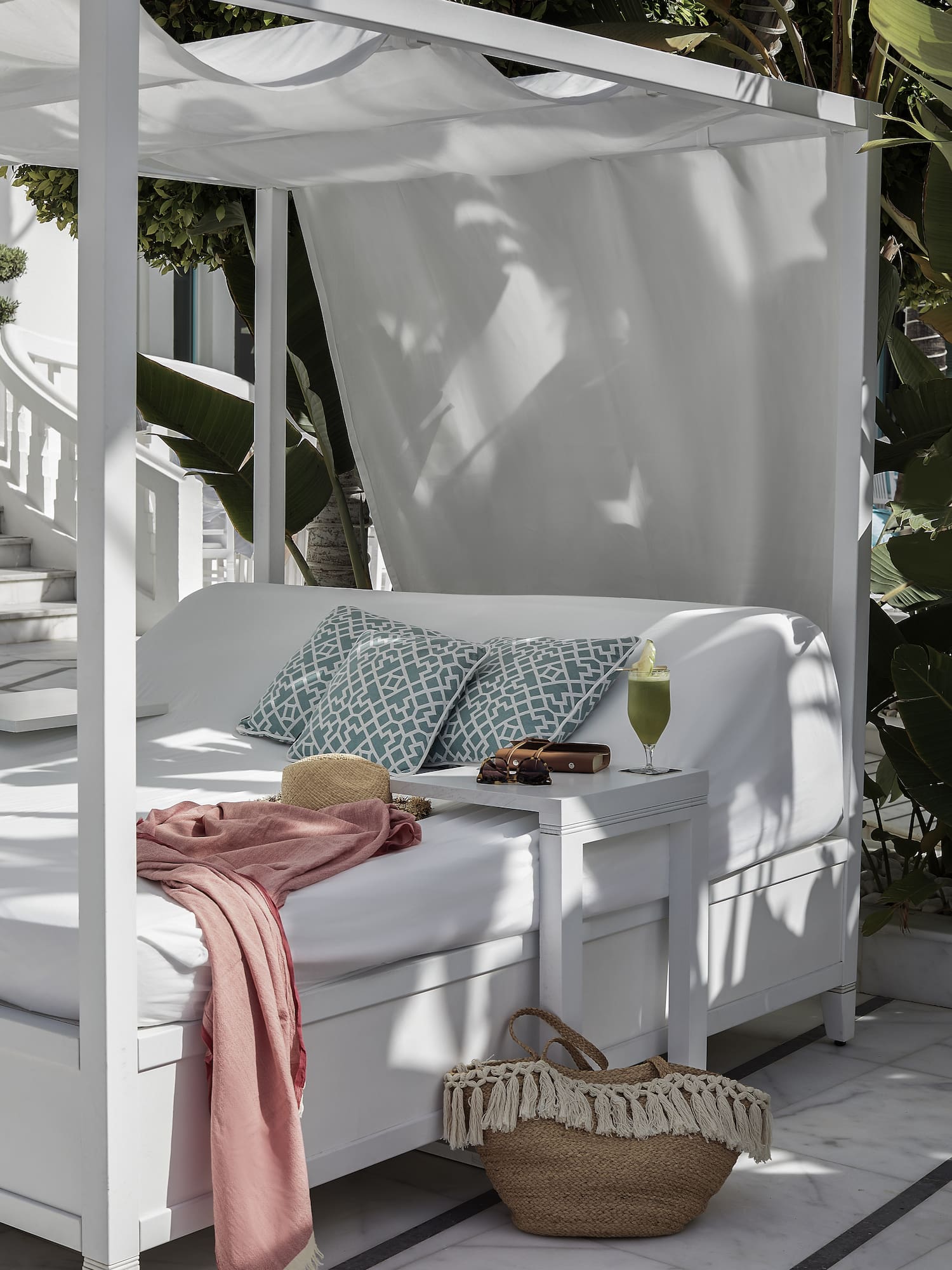 a white canopy bed with a pink blanket and a pink blanket on it