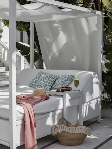 a white canopy bed with a pink blanket and a pink blanket on it