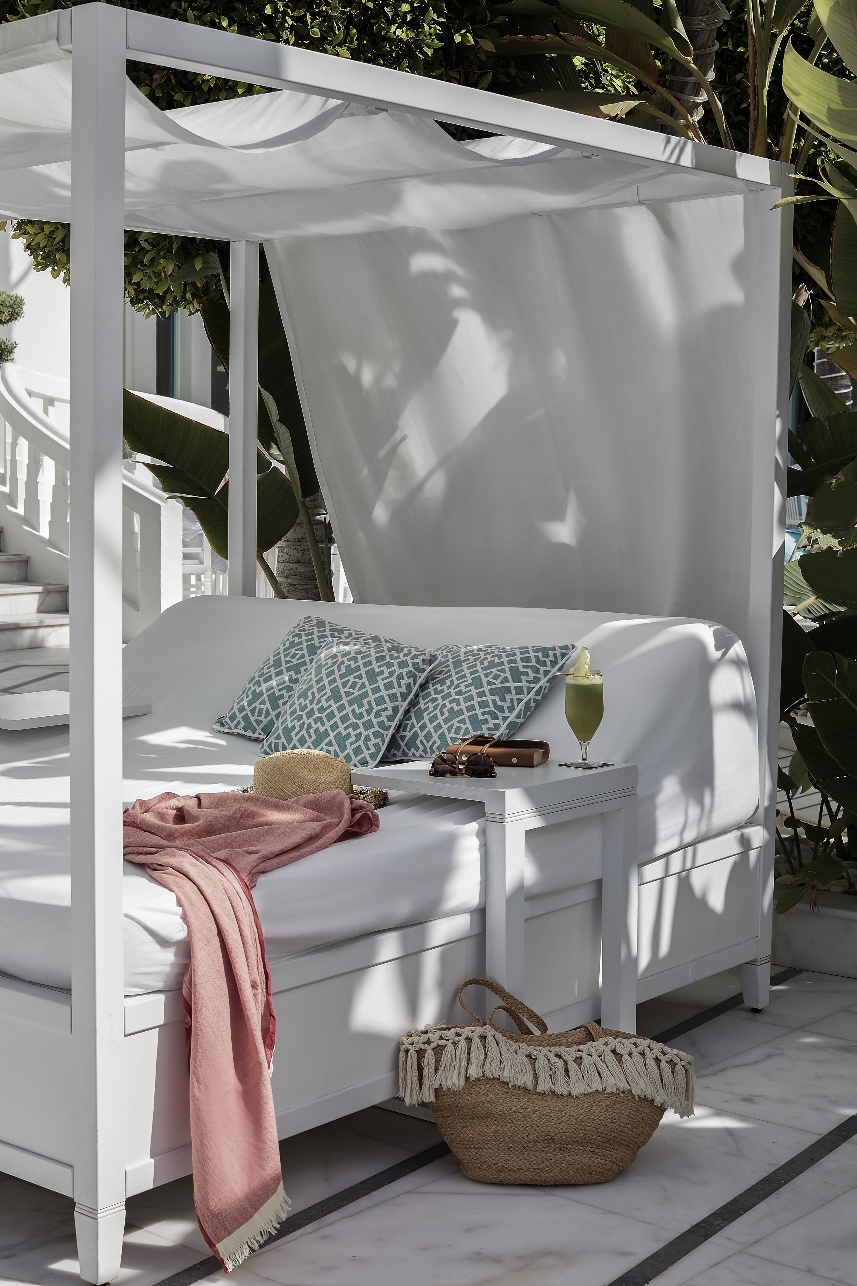 a white canopy bed with a pink blanket and a pink blanket on it
