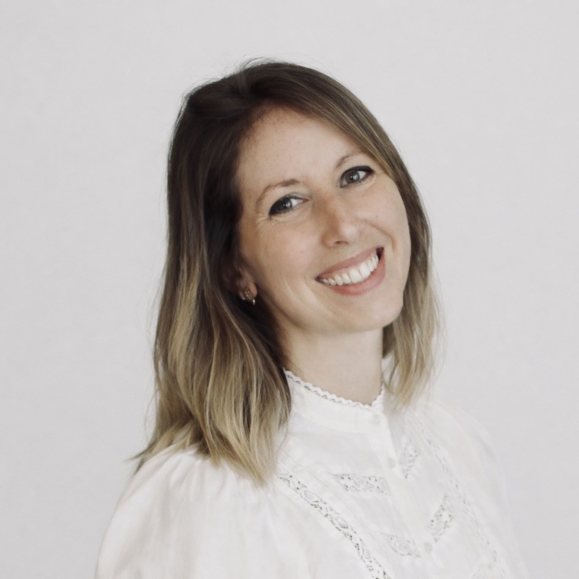 Retrato de mujer sonriendo, blusa blanca de encaje, cabello ombré.