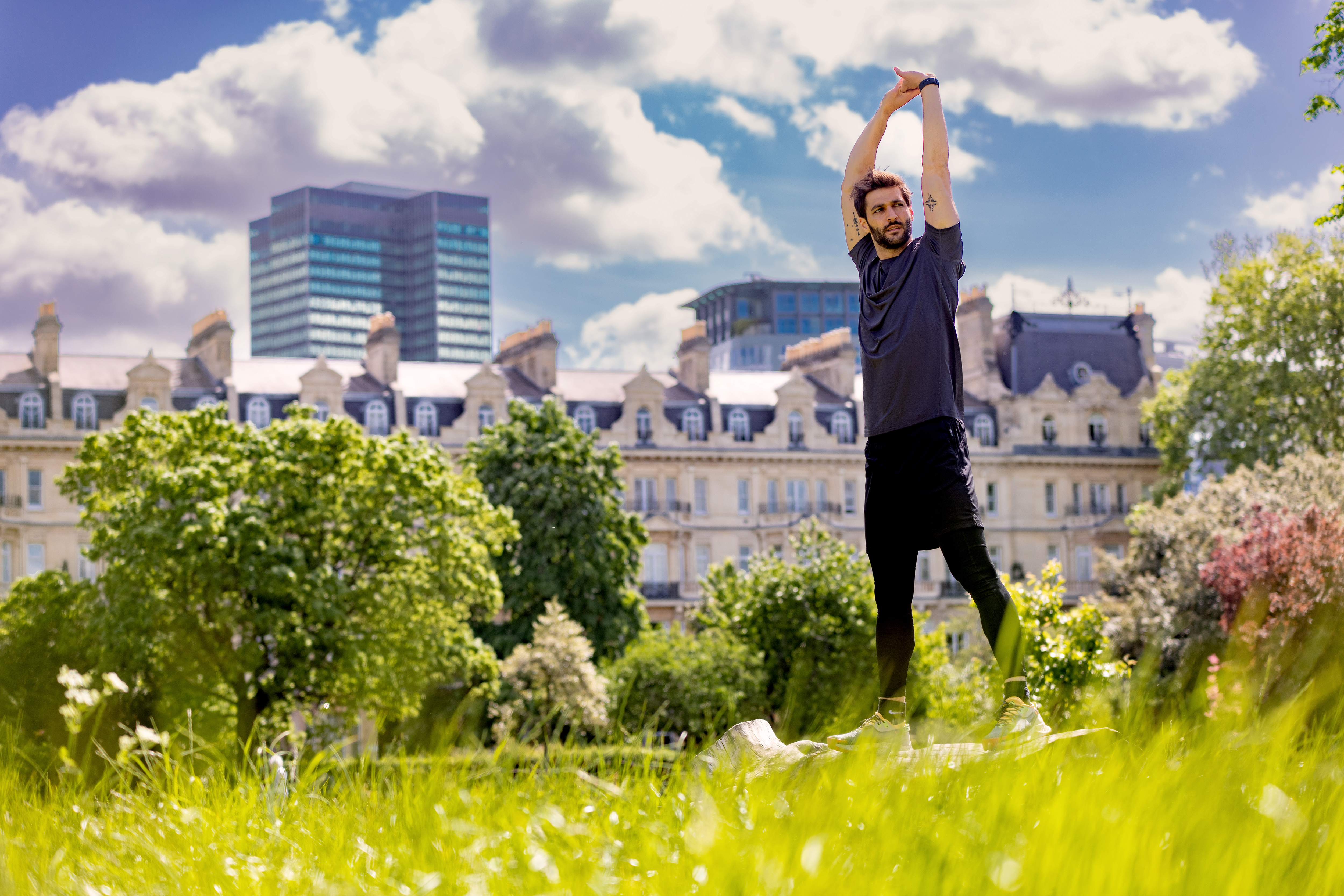A man stands in a grassy spot with his arms lifted.