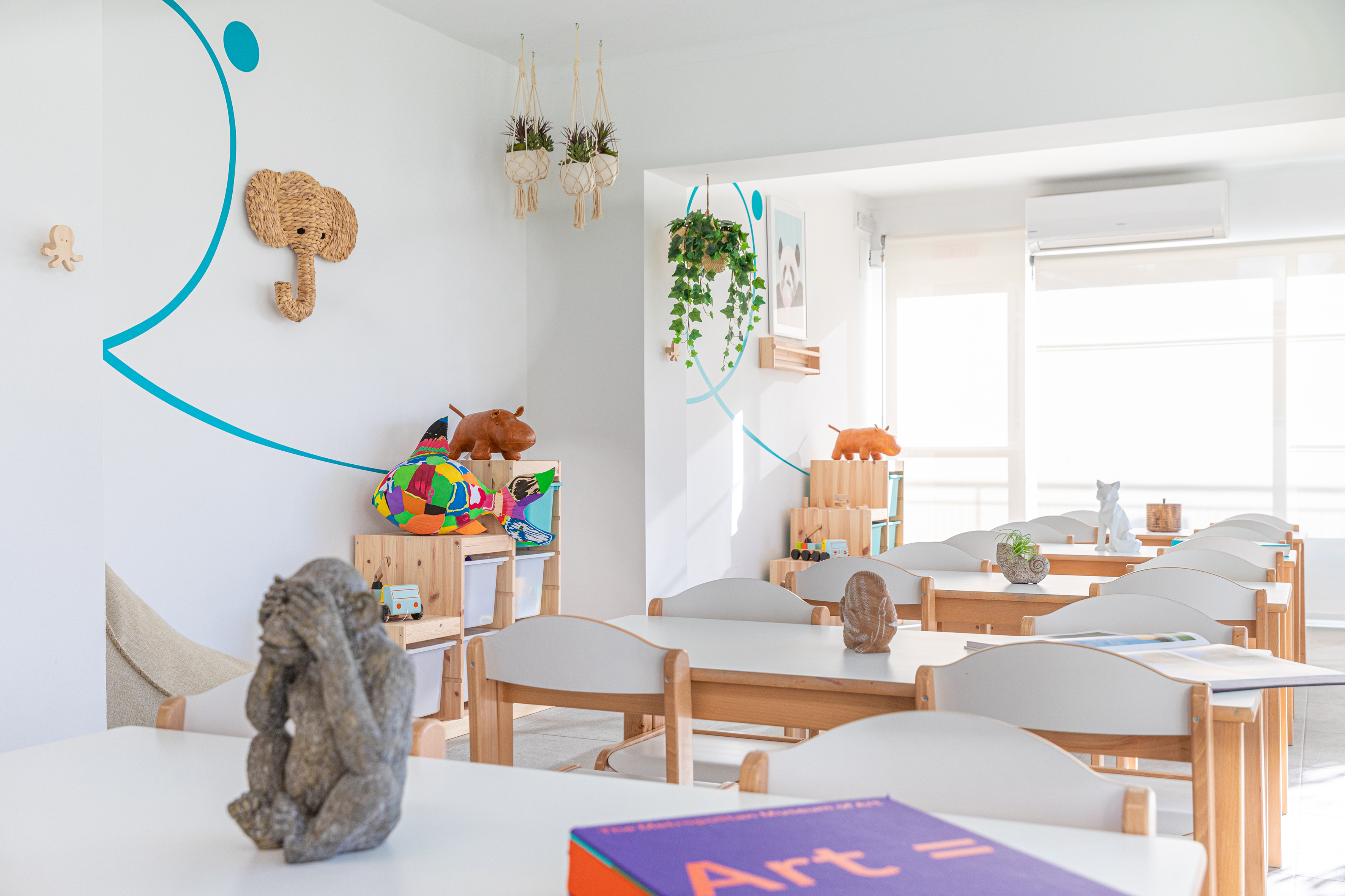 Early learning classroom with small tables, chairs, and playful animal decor.